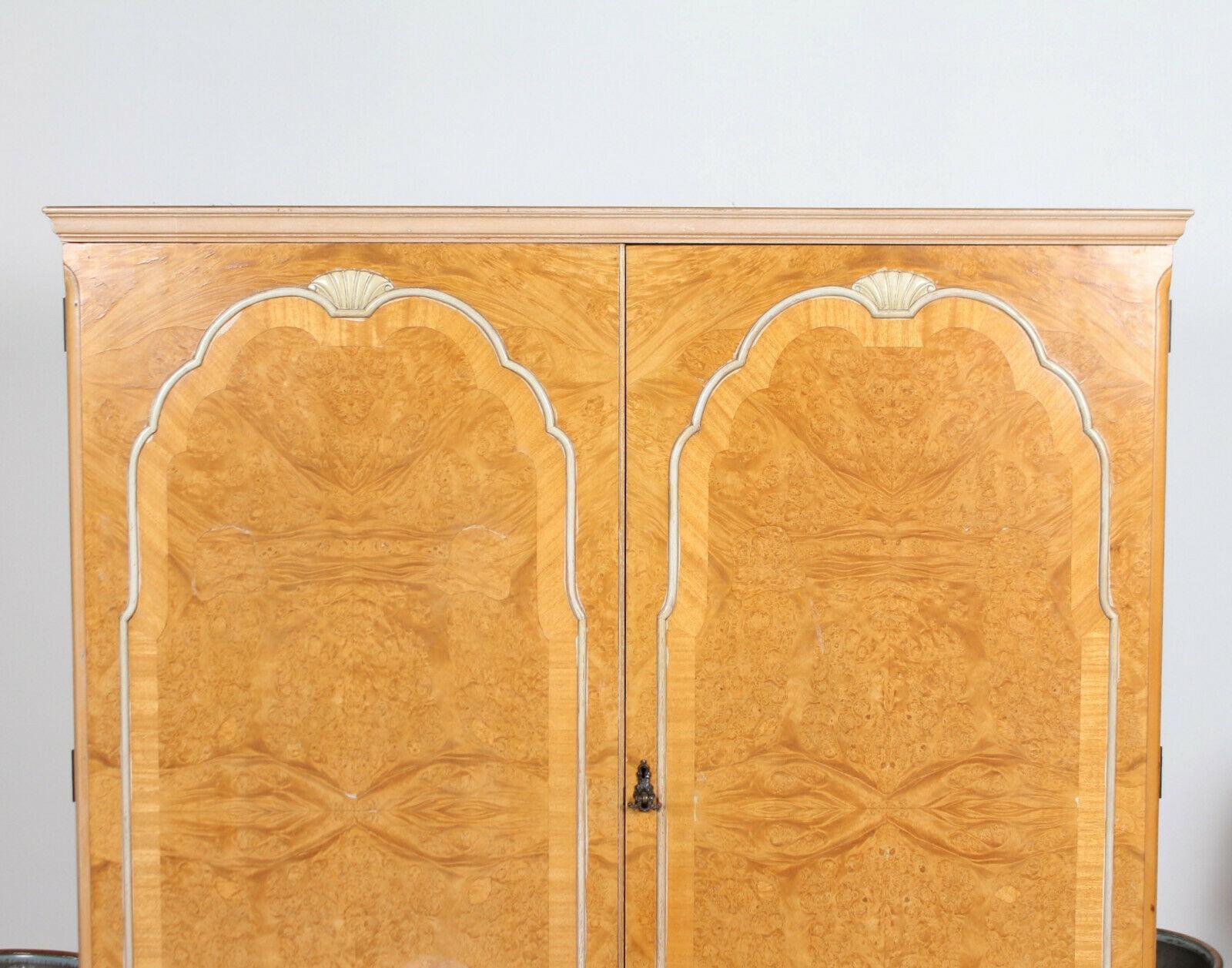 An impressive bird's-eye maple wardrobe.

The top with shaped edges above bead paneled doors enclosed hanging rails, shelving and full length mirror. Raised on carved squat cabriole legs.