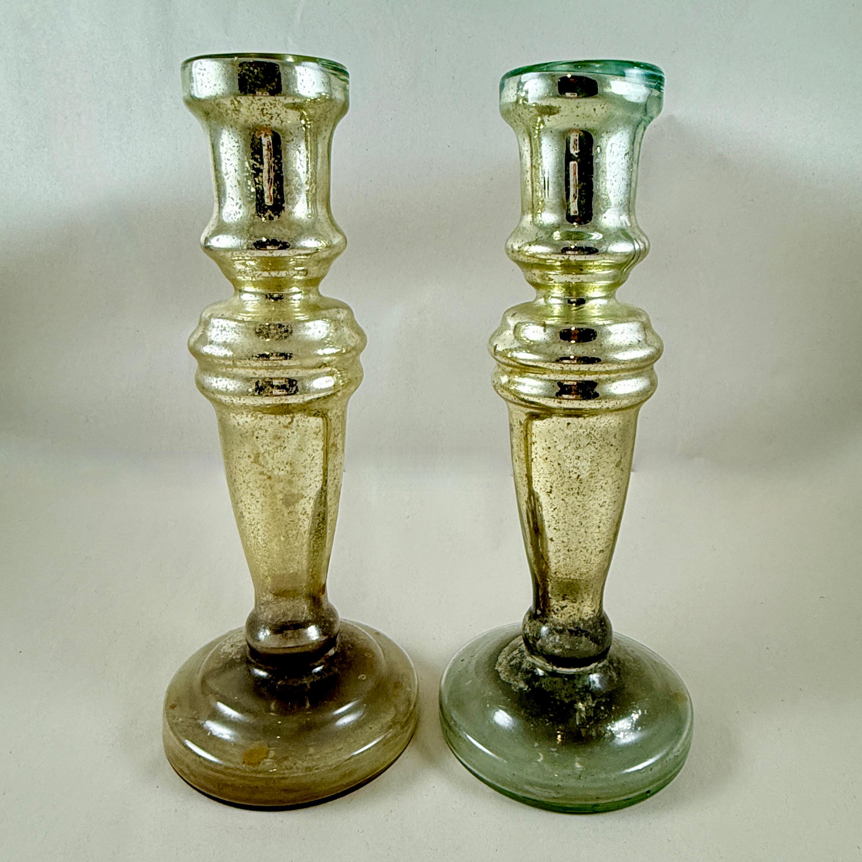 A pair of tall Silvered Mercury Glass candlesticks, England, circa 1840-1855.

Silvered Mercury glass is mouth-blown, double walled, then silvered between the layers with a liquid silvering solution. The silvering is a heated solution of silver