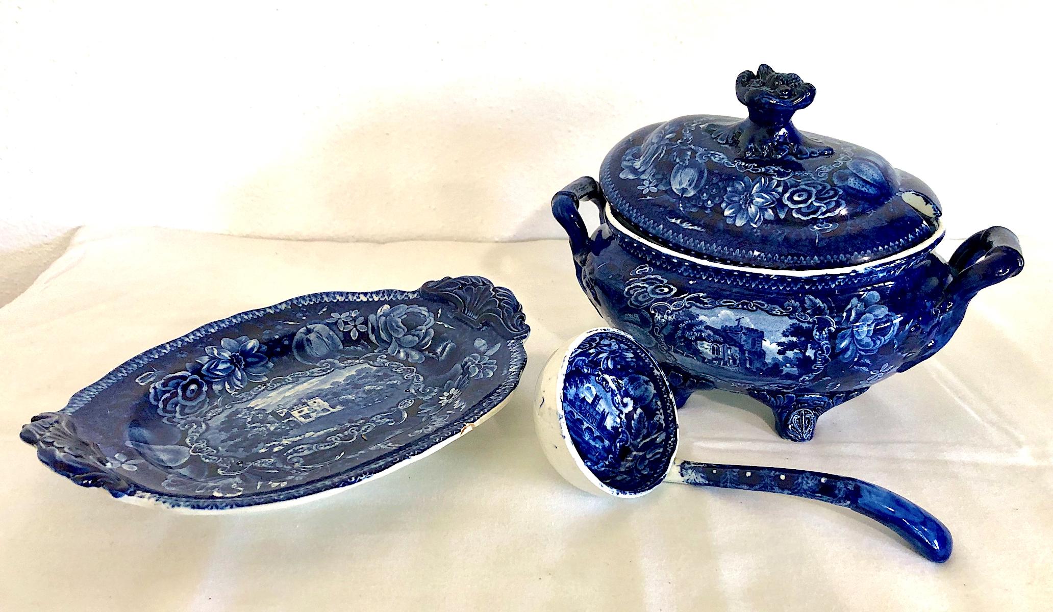 On offer is that rarity, a Staffordshire-style tureen which still retains its original lid, serving spoon and stand. Each piece displays exuberant foliage framing idealized architectural scenes, rural surroundings and vistas, all applied by the