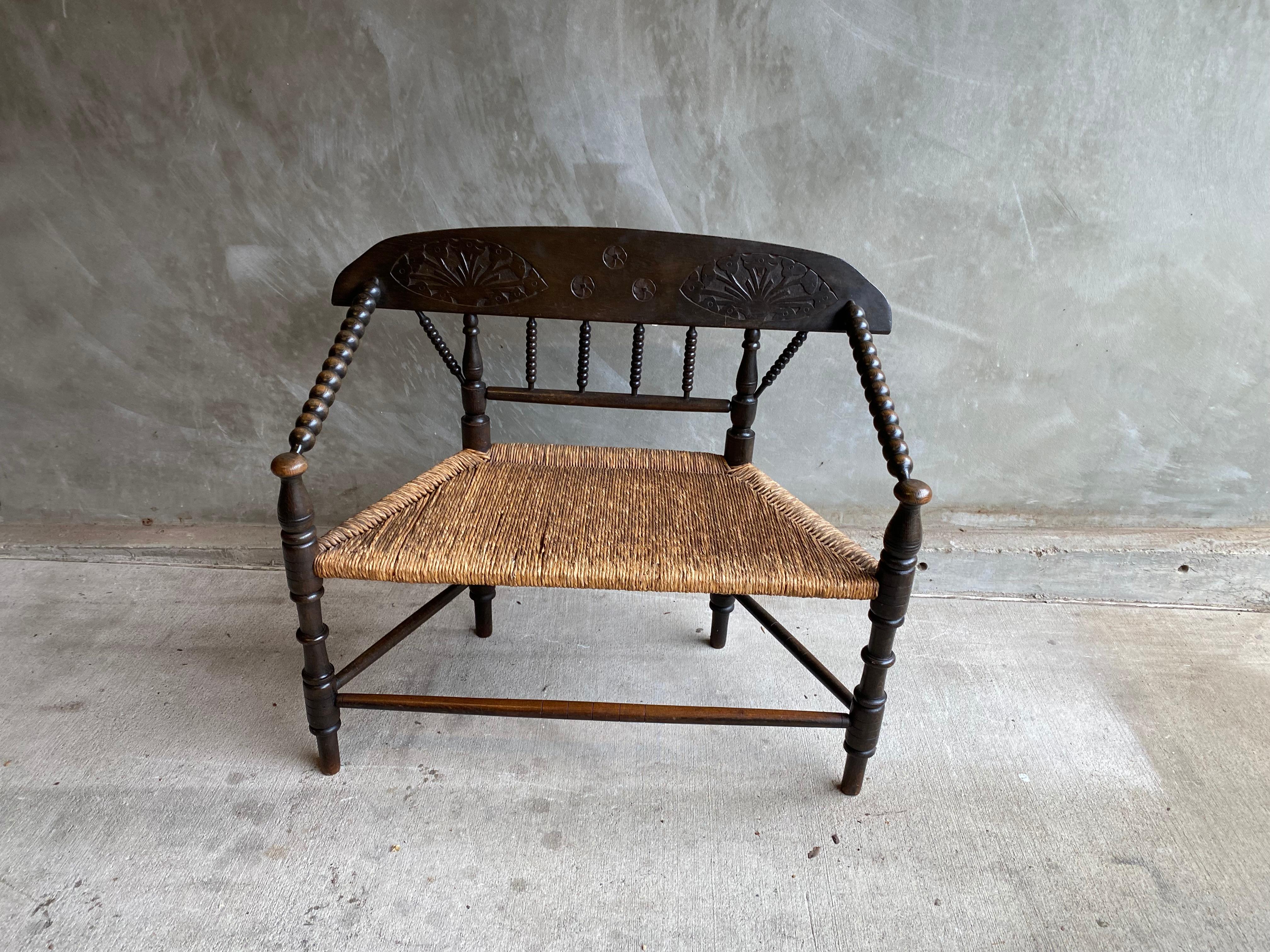 19th century settee in English bobbin style with rush seats and dark stain over oak. Matching pair of chairs sold separately. See listing LU1140228813522.