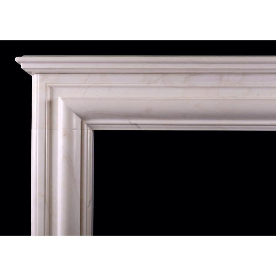 An English bolection fireplace in white marble. The jambs and frieze with moulding throughout, surmounted by moulded shelf. Unusually deep design for the style adding the benefit of a mantel. Modern. N.B. May be subject to an extended lead time,