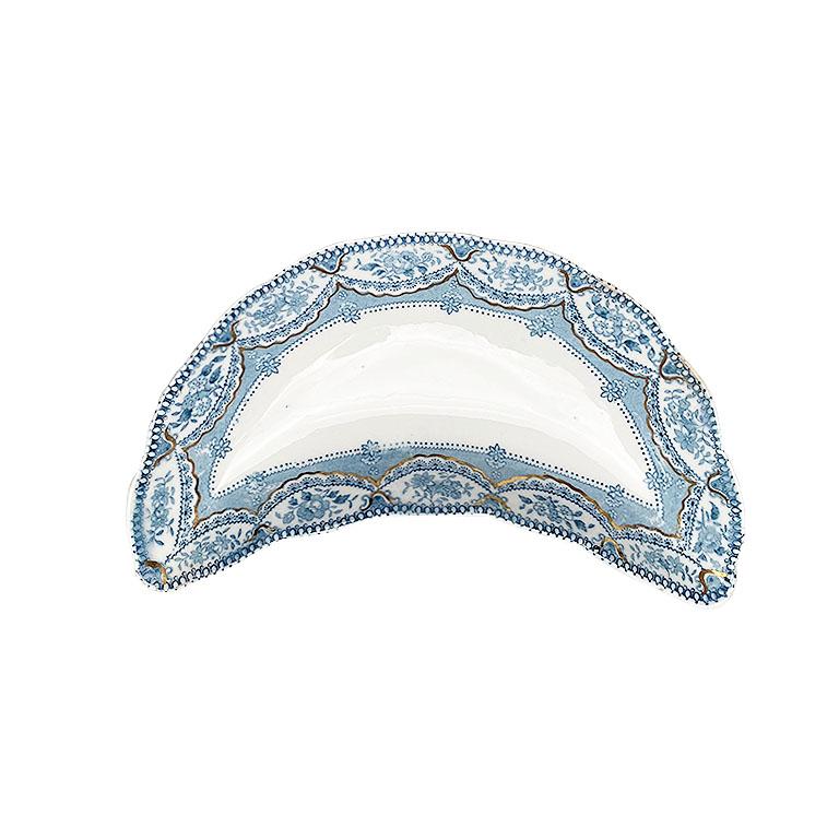 A set of five antique English bone plates. This lovely set of plates are shaped in a crescent shape and designed to sit neatly beside dinner plates to hold bones or other unwanted bits away from the diner. They are decorated in a blue floral motif