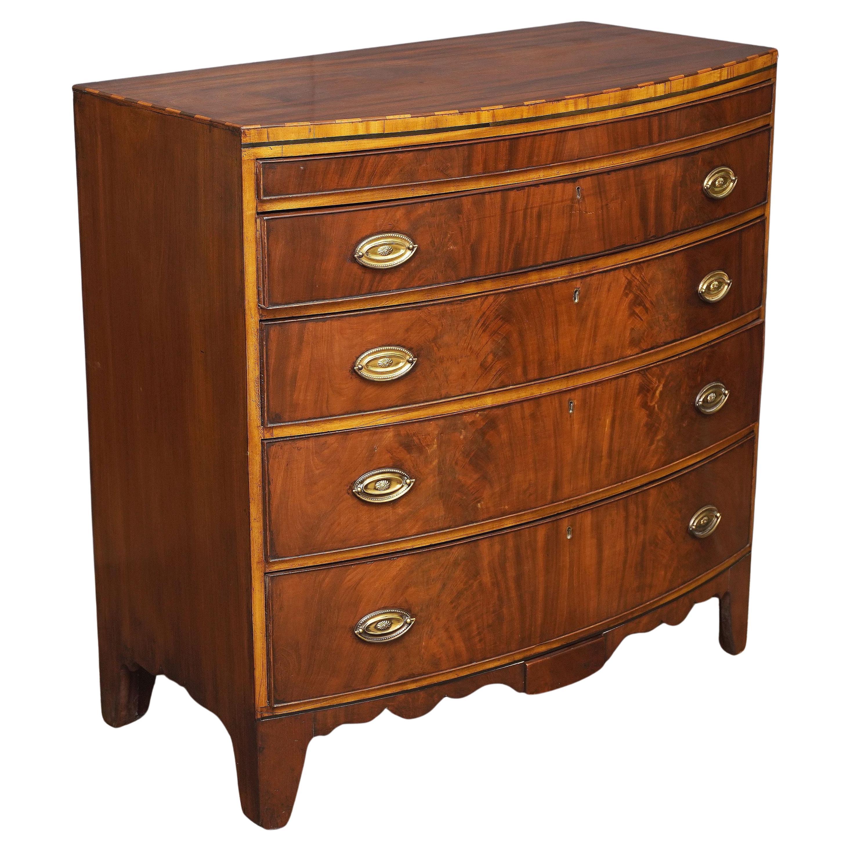 A fine English bow fronted chest of drawers of inlaid mahogany, with two secret drawers, from the 19th c century.

Featuring a bowed top with an inlaid trim around the facing top edge, over a frieze of four beaded long drawers, the drawers showing