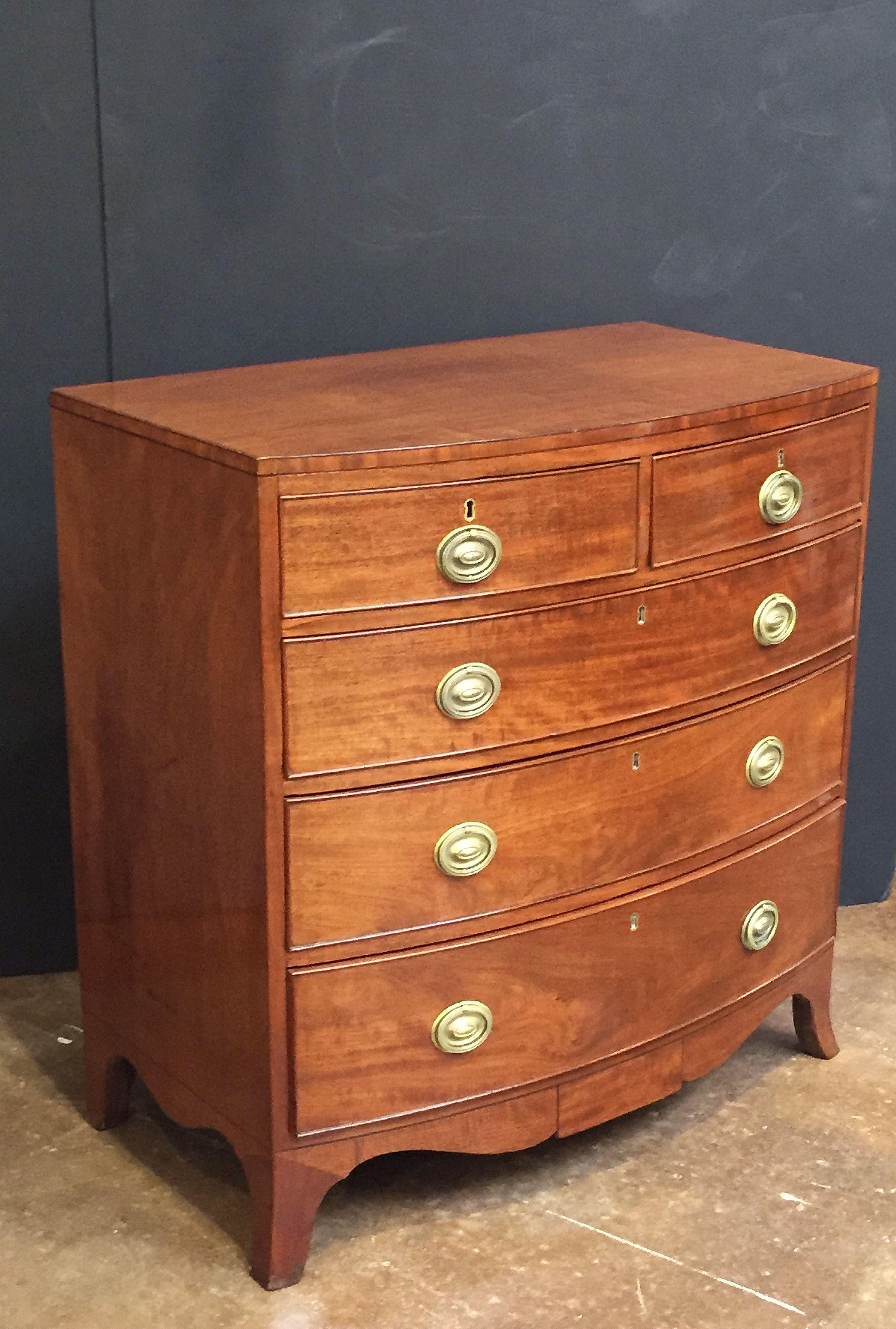 A handsome English bow-front chest of drawers of mahogany from the George III period, featuring a bowed top over a frieze of two small beaded drawers and three beaded long drawers, with oval brass pulls, and set upon a serpentine splayed foot base.