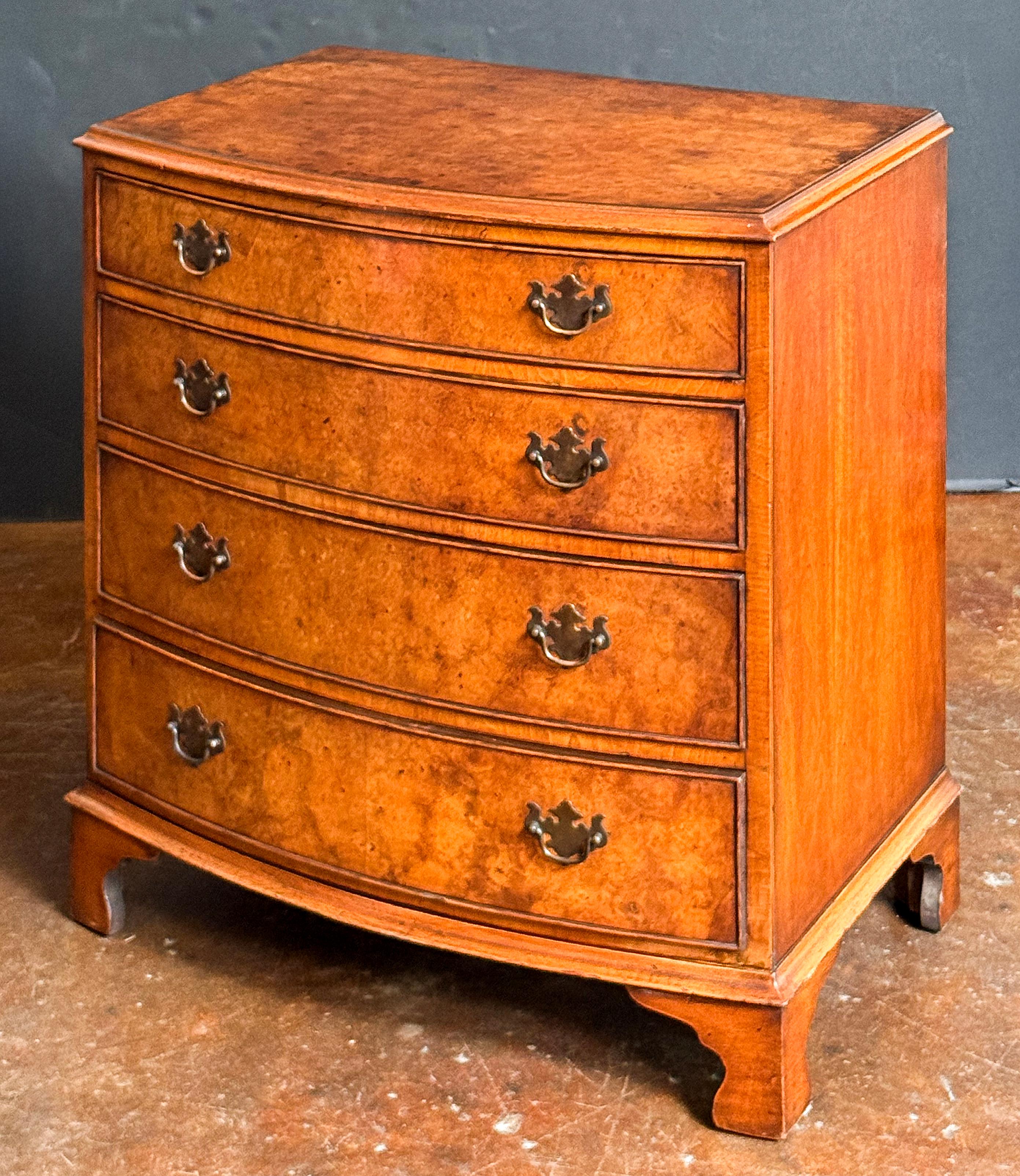 A handsome English bow-fronted small chest of burr or burled walnut from the Edwardian era, featuring a moulded top over a frieze of four graduating beaded drawers, each with original brass handles, the whole raised on bracket feet.

Dimensions: H