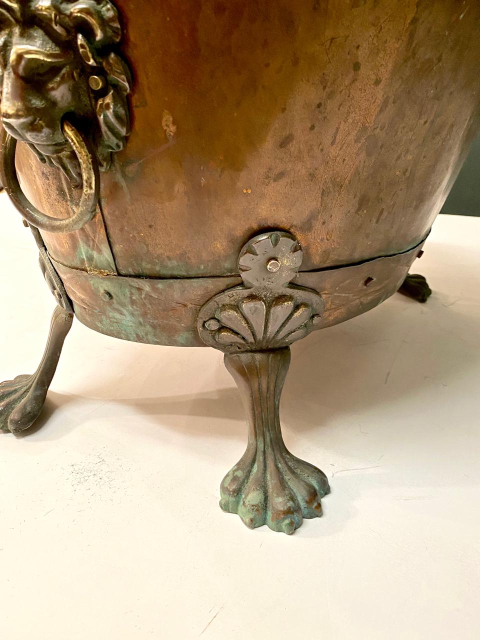 This mid-19th century English coal bin has seen many years of use and has acquired a deep, natural and desirable patina to its copper bin. The lion head side handles together with the lion paw feet make this a great decorative element.