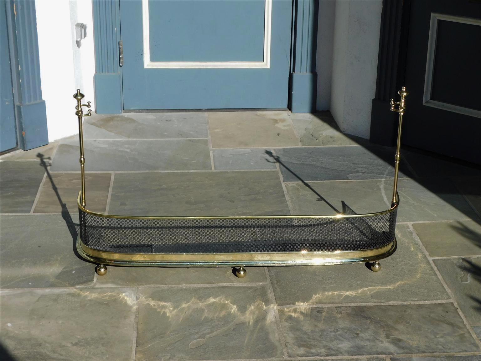 English brass and polished steel fire place fender with a decorative pierced gallery, original flanking bulbous finial tool holders, interior iron pan, and resting on the original three ball feet. Early 19th century
Fender height on each end with