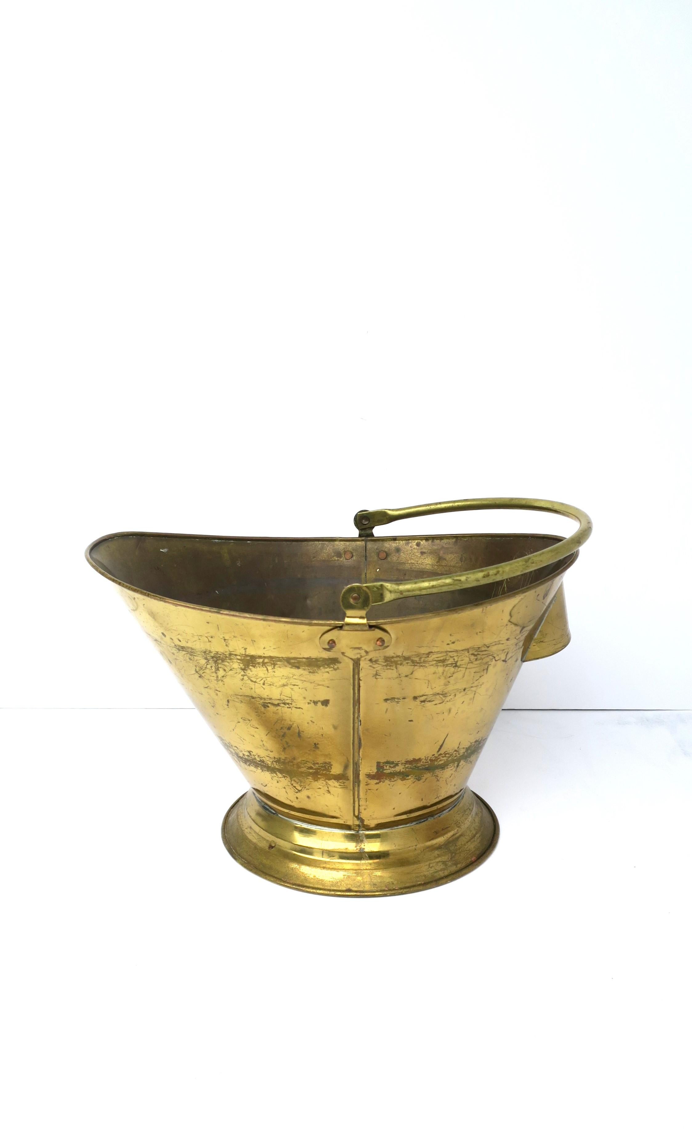 An English brass coal scuttle fireplace pot bucket, circa early to mid-20th century, England. Marked 'England' on underside as shown in last image. Bucket pot has flexible top handle and rear handle for easy lifting/emptying. Bucket has a lacquered