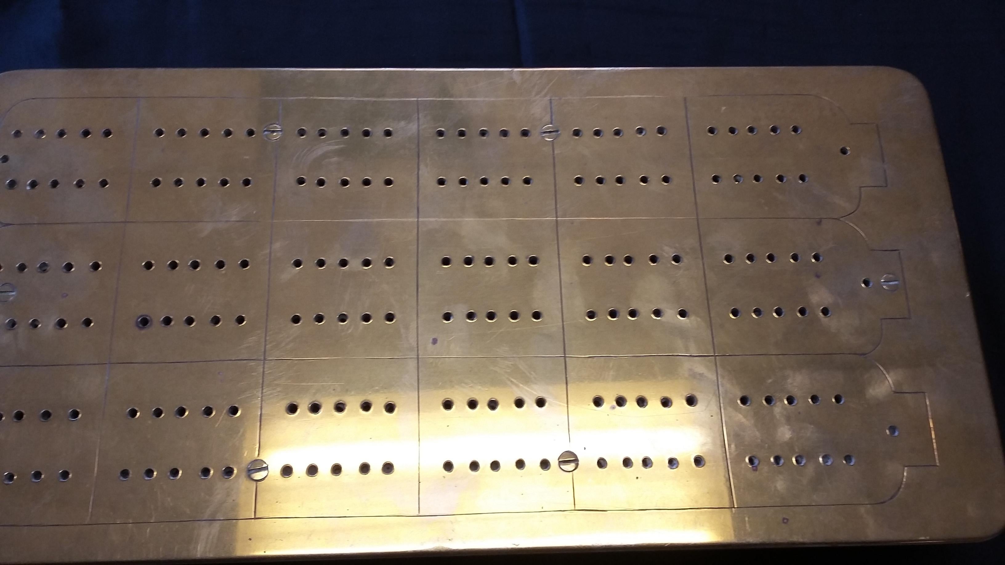 Very unique brass cribbage board. Made in England, circa 1880. The underside of the brass board might be rosewood(?). Case with working sliding compartment for cribbage pegs. Only 4 pegs included. Who knows who may have used this years ago?