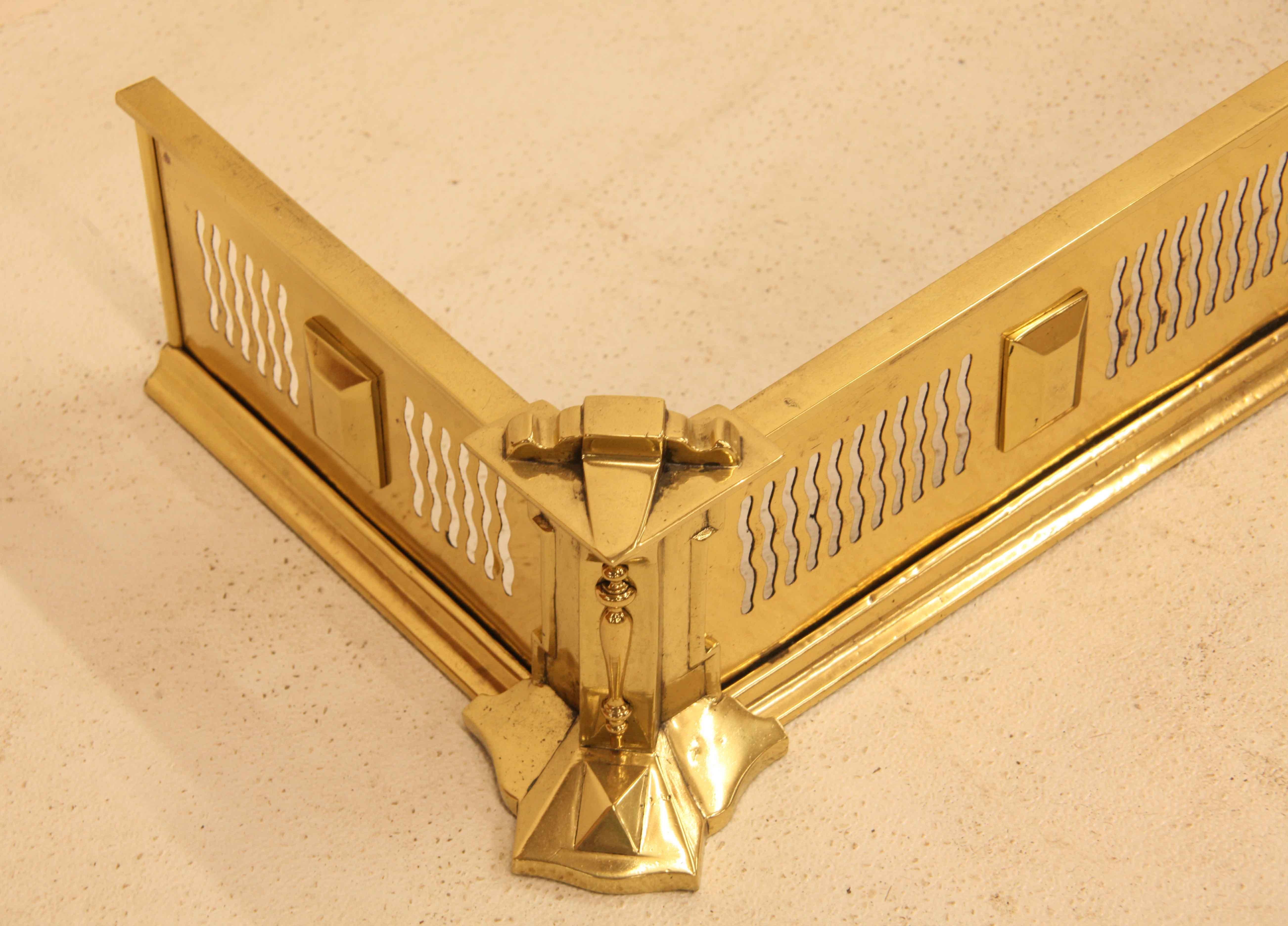 English brass fender,  with a repeating reticulated wavy pattern separated by applied raised blocks; canted corners with projecting molding and design.   The interior measurements are 48.25'' wide and 11.5'' deep.  