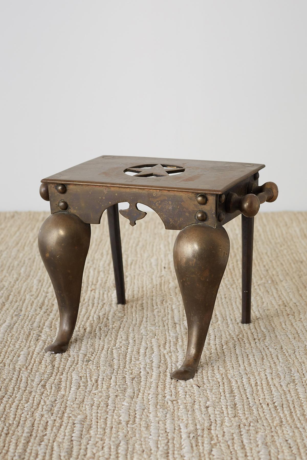 Antique English brass fireplace stool or footman trivet originally used as a Stand for keeping plates warm by a dining room fire. Also known as a hearth stand, fireside trivet, or coach step. Thick construction is very substantial and heavy with