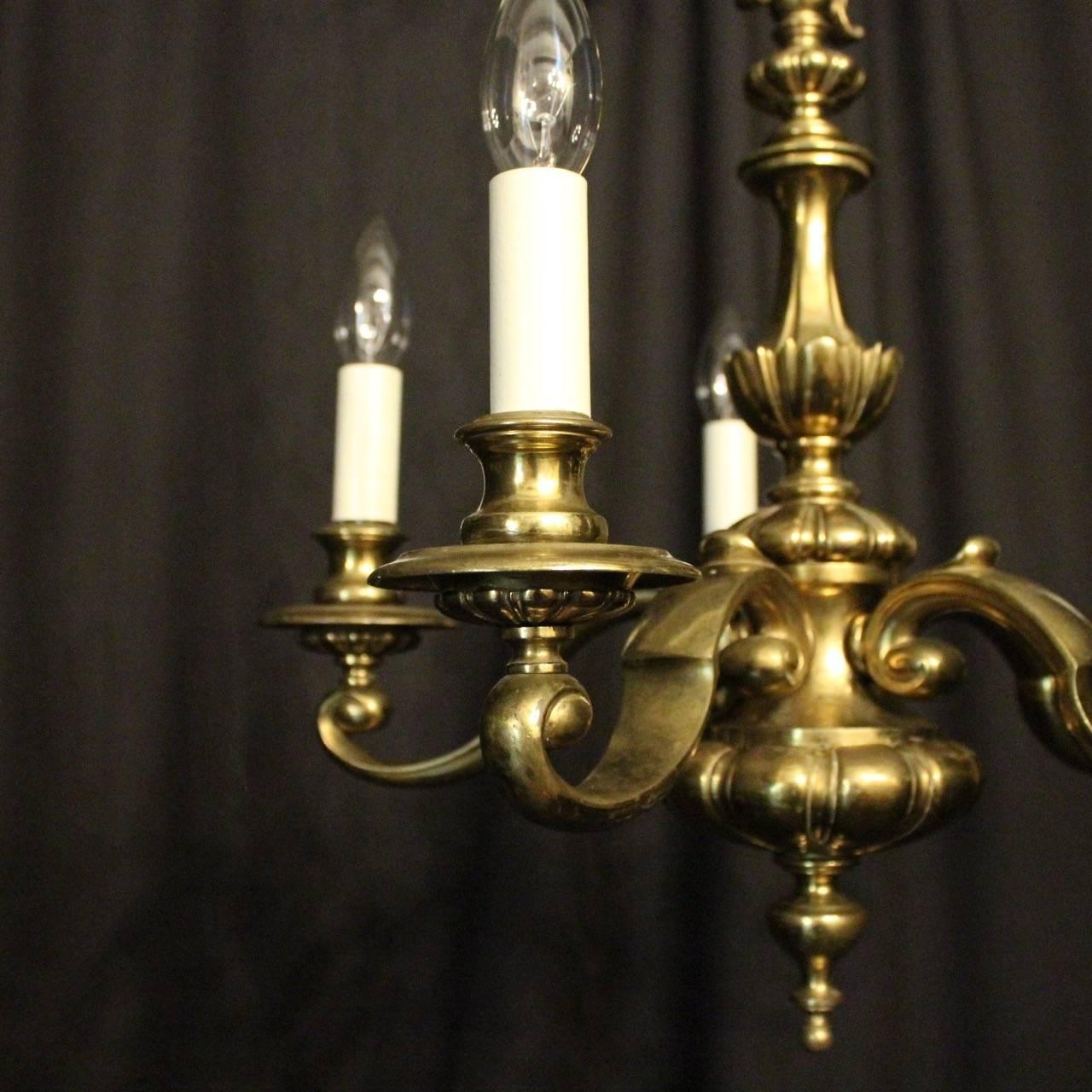 An English brass five-light antique chandelier, the decorative scrolling arms with circular bobeche drip pans and bulbous candle sconces, issuing from an ornate reeded bulbous central column, having the original ceiling rose with lovely original