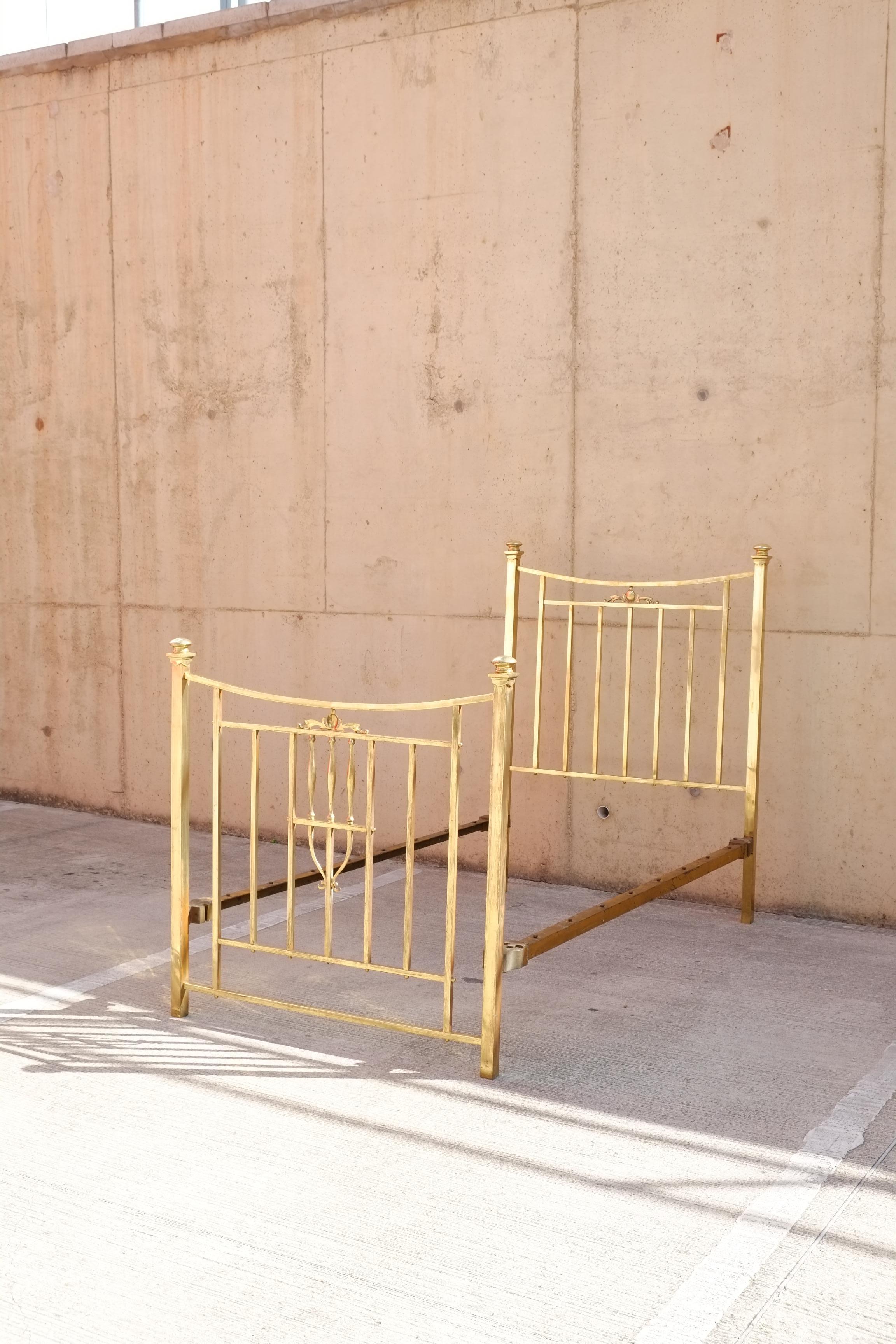 Una bellissima struttura letto in ottone e ferro dei primi del Novecento. Il letto in ottone ha un design elegante con sottili fusi squadrati e una decorazione ovale monogramma sulla testata e sulla pediera con la lettera V incisa. Splendida