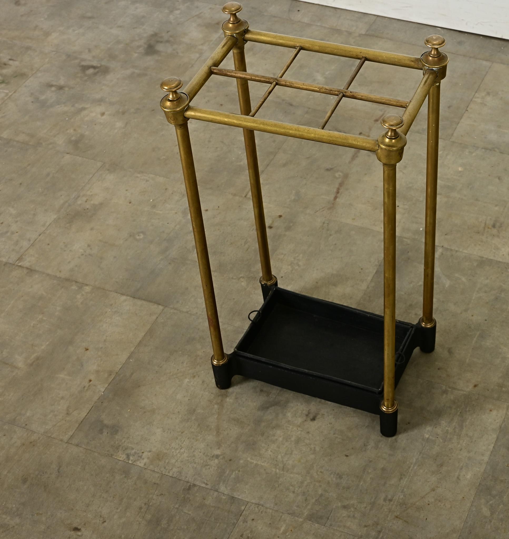 There are no rainy day blues with this charming English brass umbrella & walking cane holder from the turn of the last century. A grid of six spaces at the top is supported by four brass legs, capped with knob-like finials. The heavy cast iron base