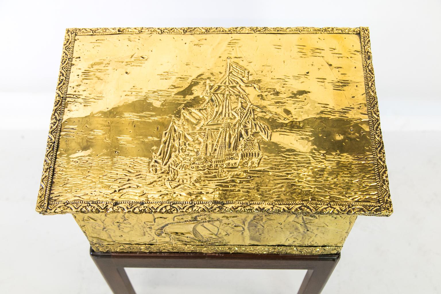 English brass kindling box on stand rests on a recently custom made mahogany stand with fretwork corner brackets. The front, top, and sides all have maritime scenes of an English galleon which are framed with brass overlay moldings.
   