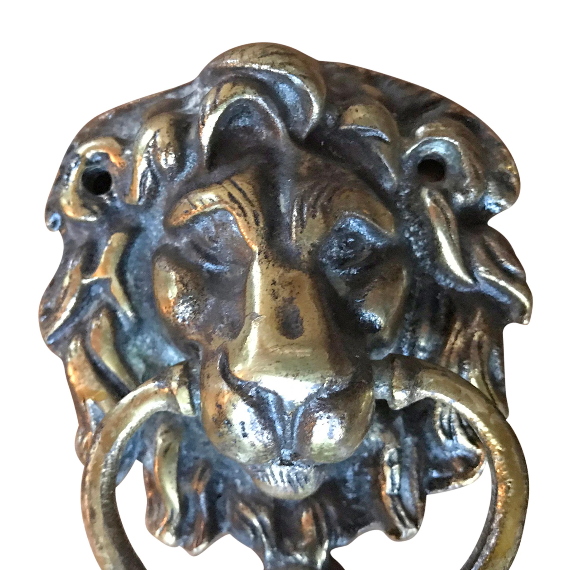An early 20th century English cast brass lion head door knocker with a ring used for knocking, and a round plate stamped with the word, 