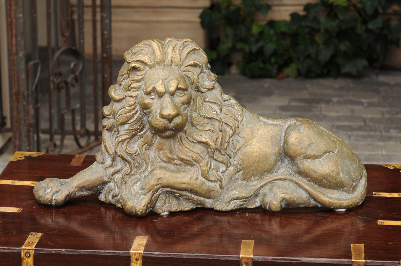 An English brass lion sculpture from the late 19th century, in a reclining position. Born in the later years of the 19th century, this English brass lion exudes an undeniable air of wisdom and strength. Looking directly at us, he is communicating