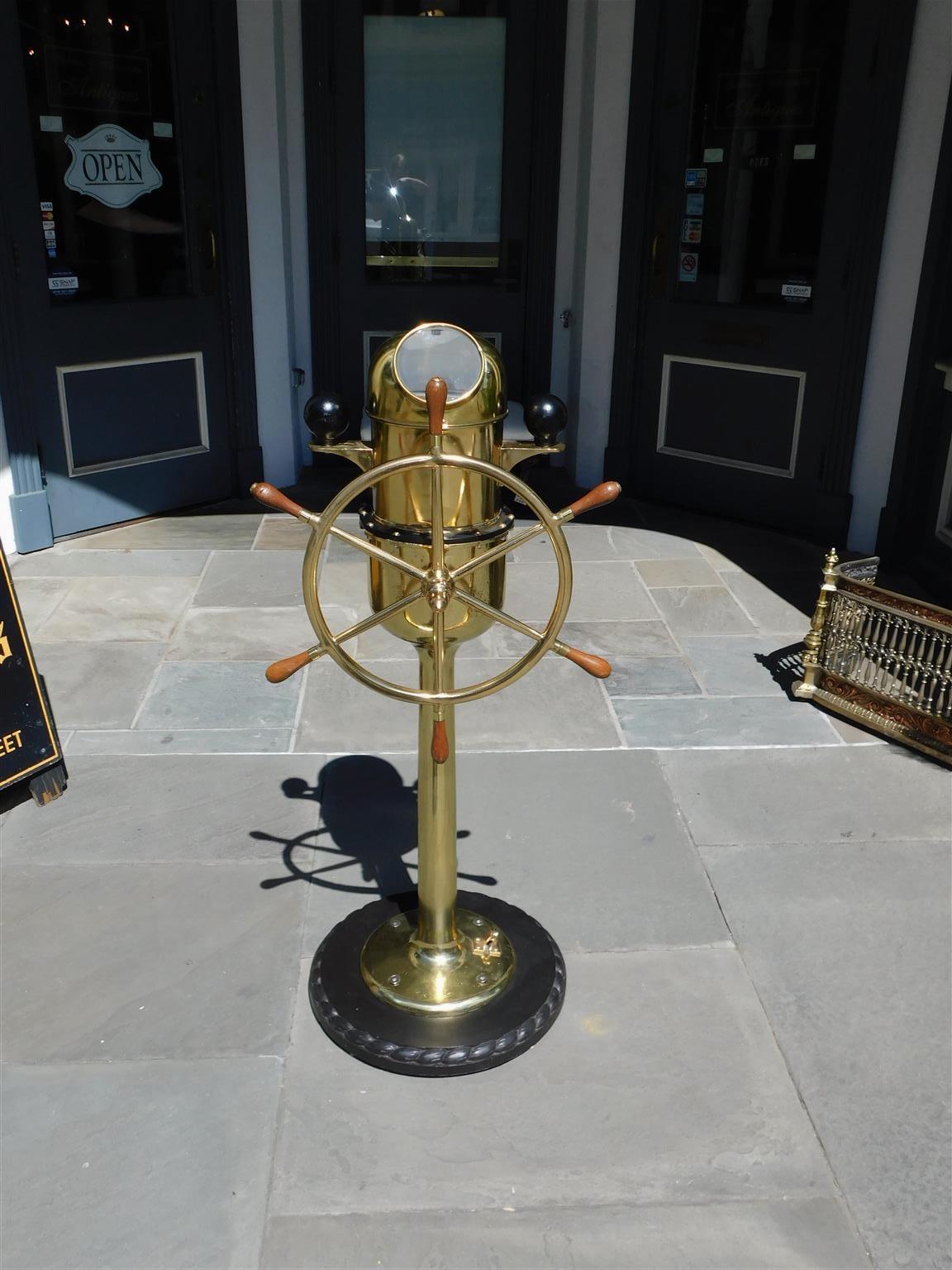 English Brass Nautical ship wheel mounted on a solid brass pedestal with an yacht binnacle having a gimballed signed compass, circular six spoke wheel with bulbous wood handles, flanking brass brackets with compensating balls, and mounted on a