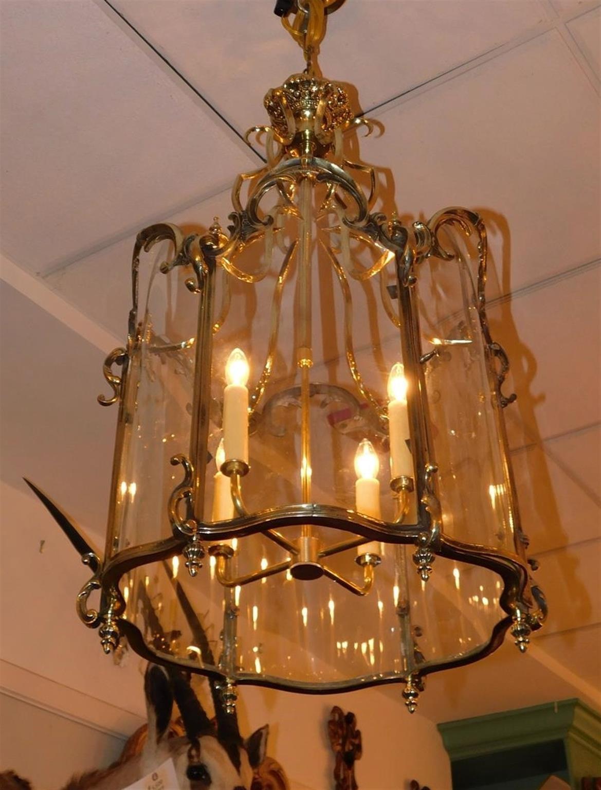 English brass serpentine foliage hanging hall / foyer lantern with a locking hinged door, flanking bulbous urn finials, scroll work, and retains the original six panel hand cut glass. Lantern was originally candle powered and has been electrified