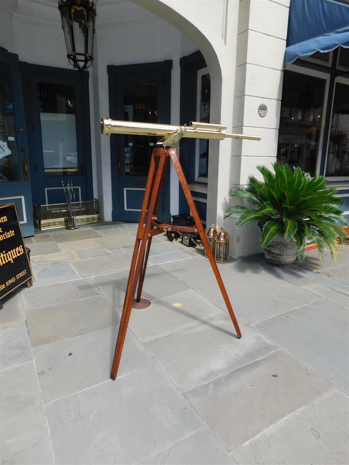 English brass telescope on adjustable oak tripod stand. Telescope retains the original glass lens, upper side sight, and lens cover. Telescope is all original and in working condition. Tripod legs are 41