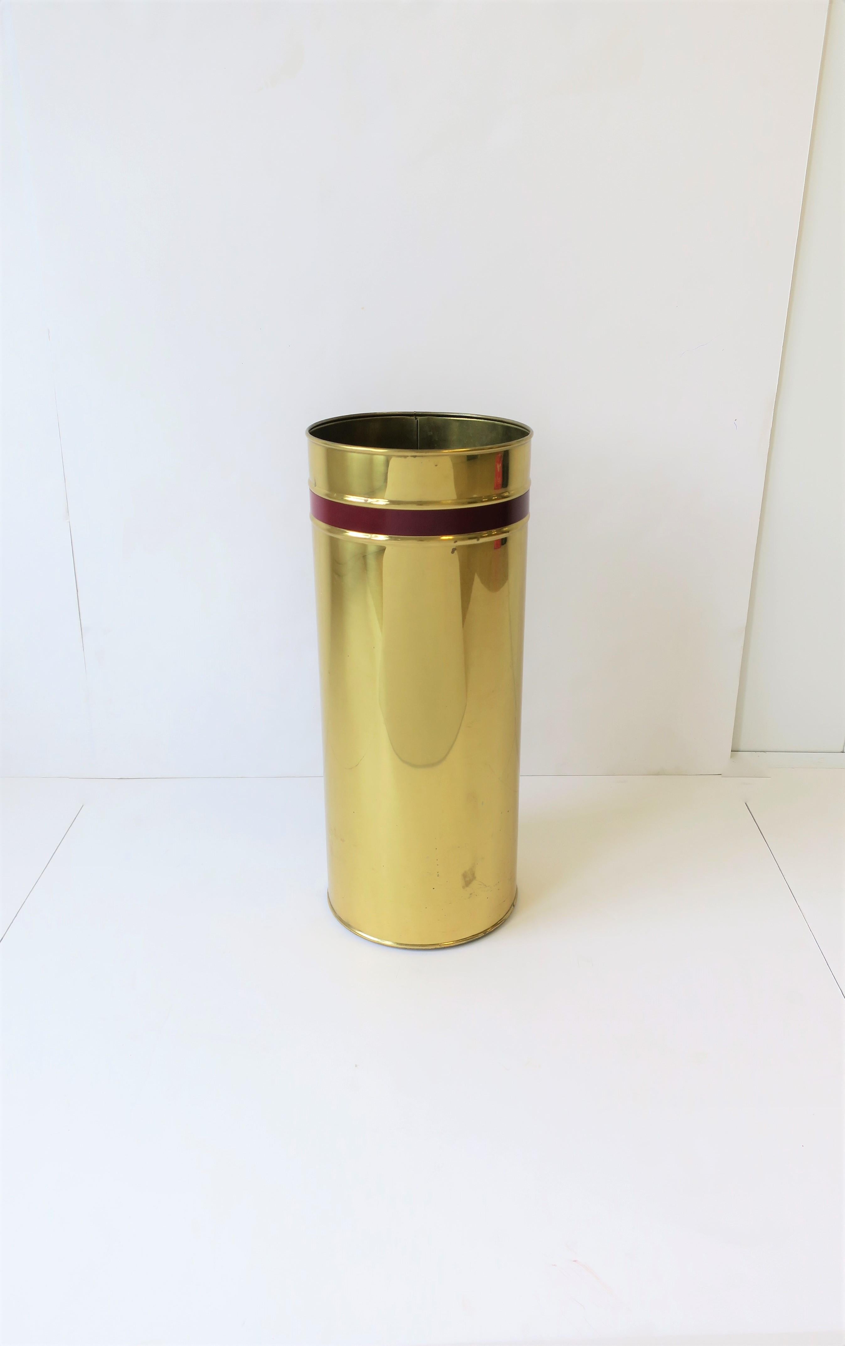 A vintage English brass umbrella stand with red burgundy decorative stripe or band, circa 20th Century, 1960s-1970s, England. Marked 'Made in England' on bottom as show in image #11 and 12. 

Measurements include: 16.25