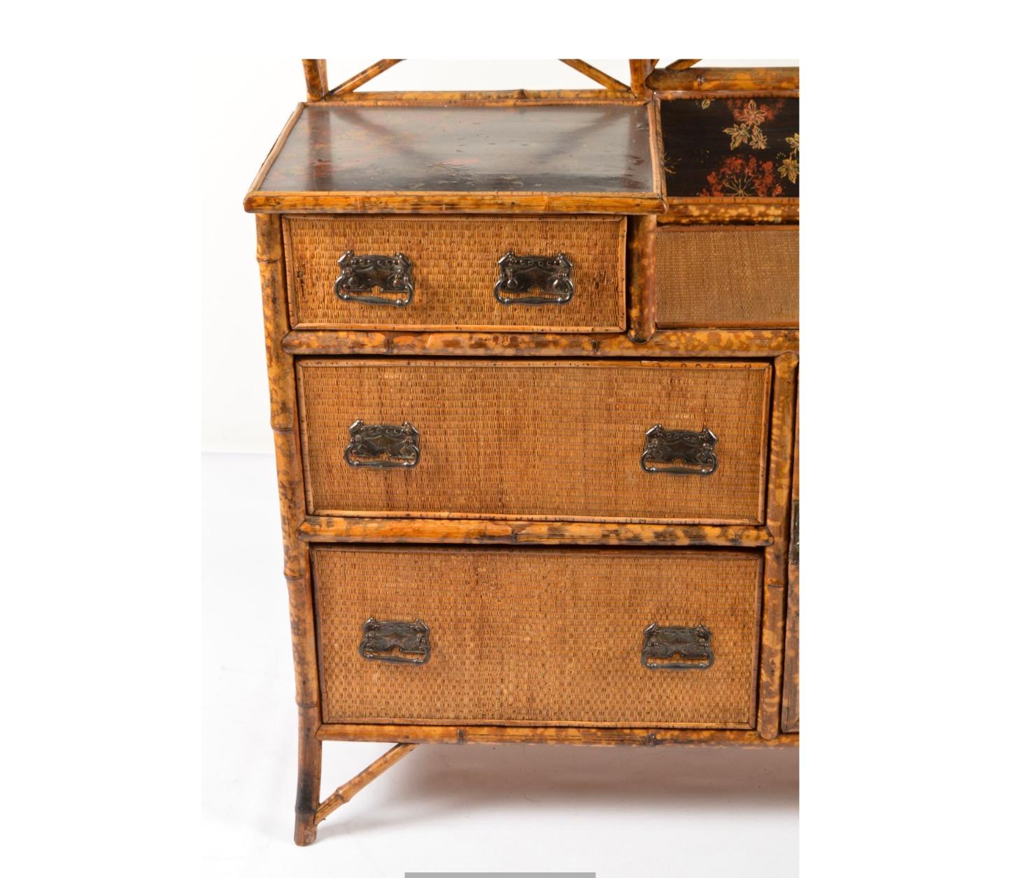 A superb antique 19th century English Brighton bamboo and woven rattan dresser vanity with lacquered Aesthetic Movement panels. To the left is a tilting, rectangular gracefully aged mirror with asymmetrical arch pediment, over a shallow shelf,