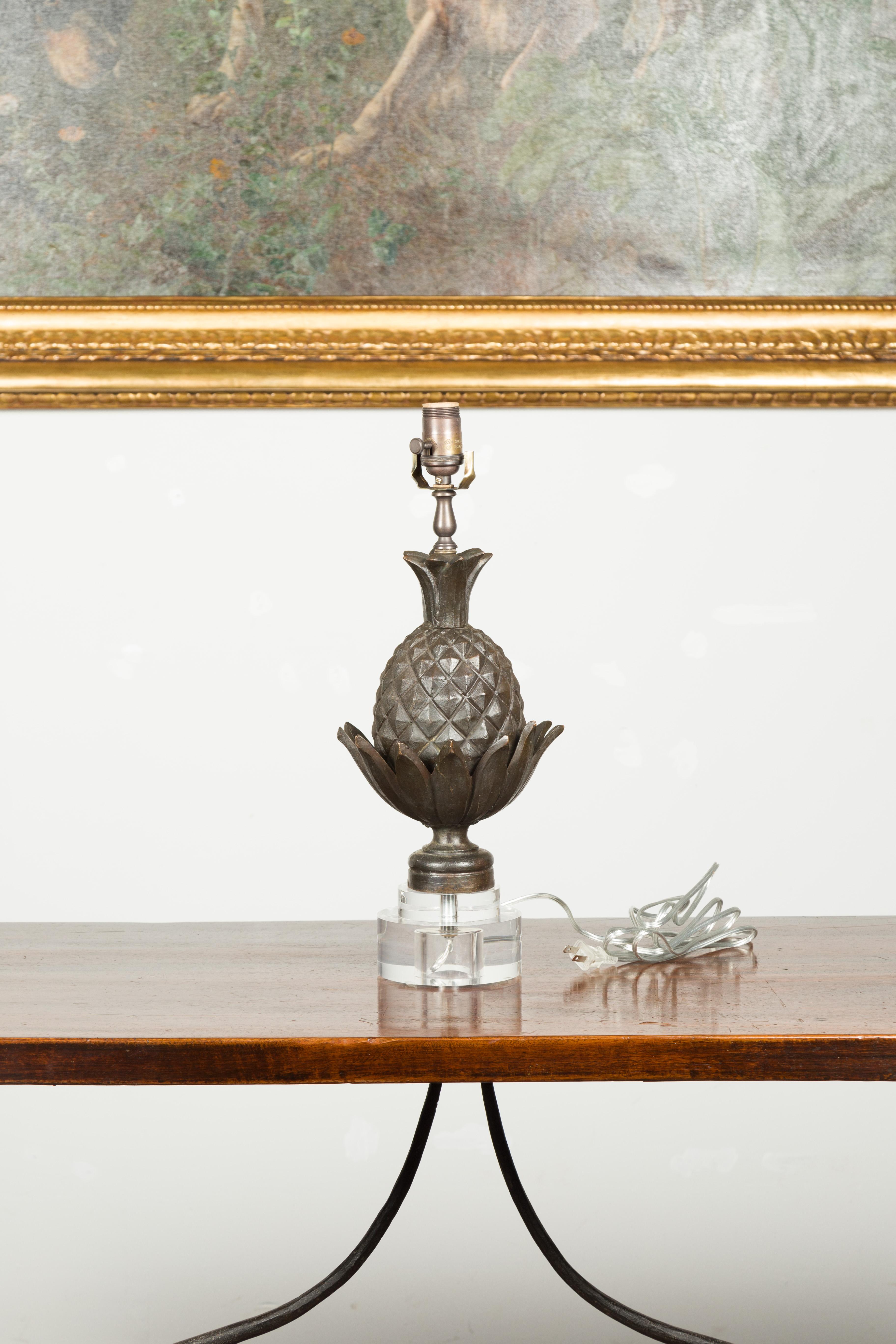 An English bronze pineapple table lamp from the mid 20th century, with lucite base. Created in England during the midcentury period, this table lamp features a bronze pineapple motif mounted on a circular lucite base. Rewired for the US, this lamp