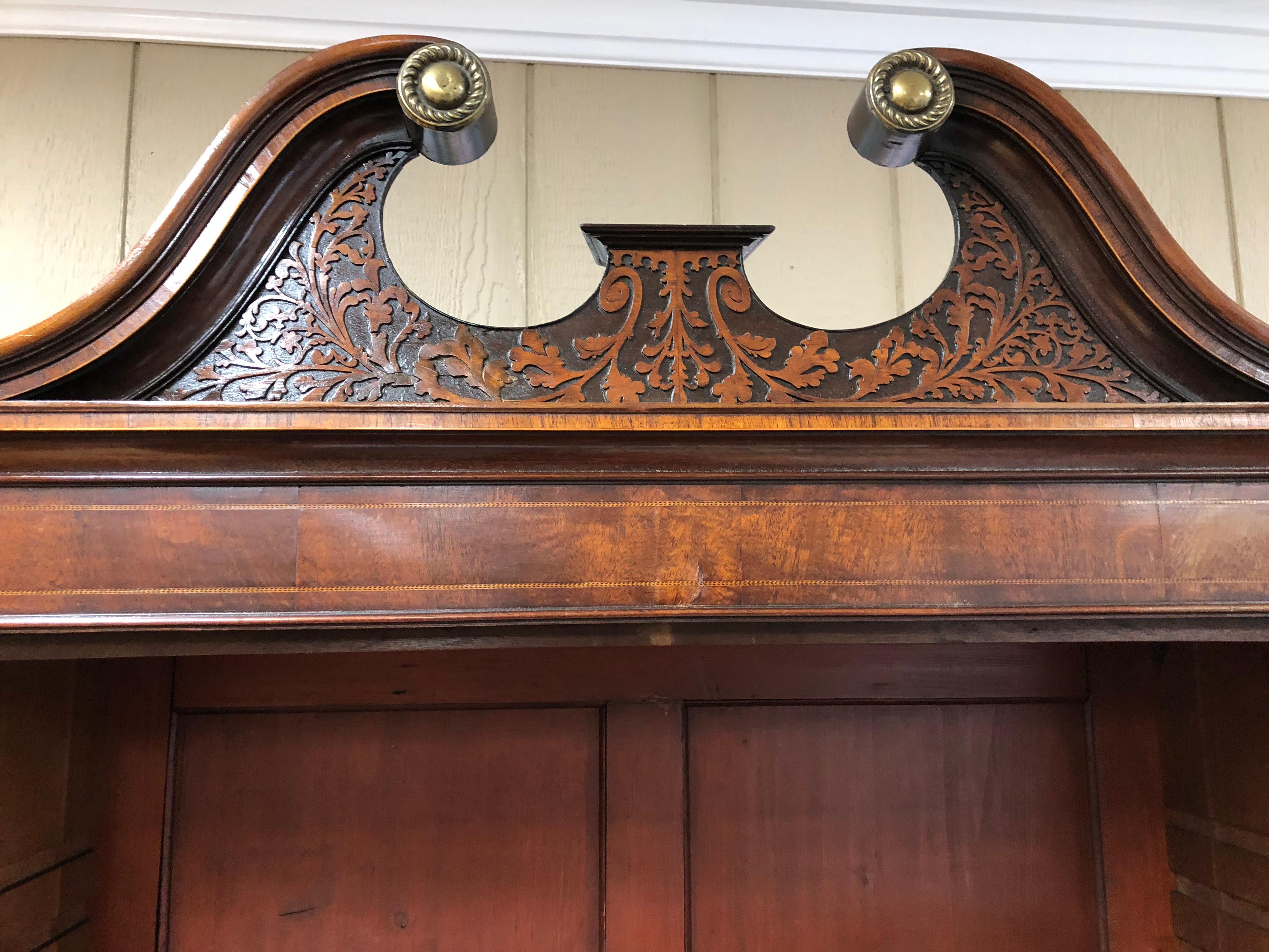 English Bureau bookcase or secretary in light mahogany. Inlays on the inside, handsome black leather writing surface with gold line, impressive swan neck broken pediment with carvings and brass rosettes. Adjustable shelves, drawers work well,