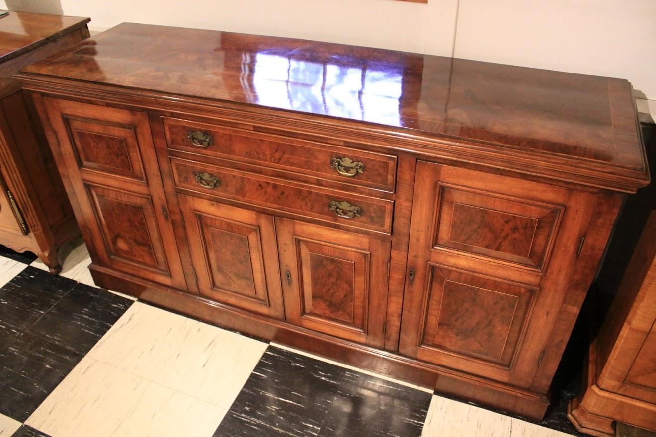 English burl walnut dresser base with two center drawers over a center cabinet, flanked by two, full height cabinets. Original brass.