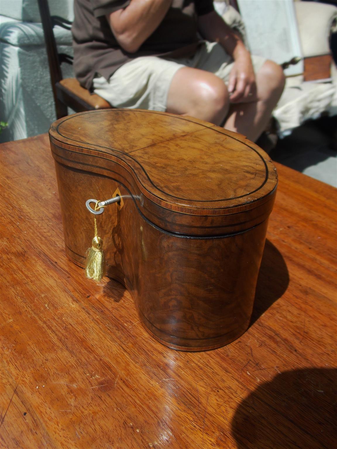 English burl walnut hinged kidney shaped tea caddy with ebony string inlay, tulip wood cross banding, diamond inlaid escutcheon with key, and fitted with original foil lined interior, Early 19th century.