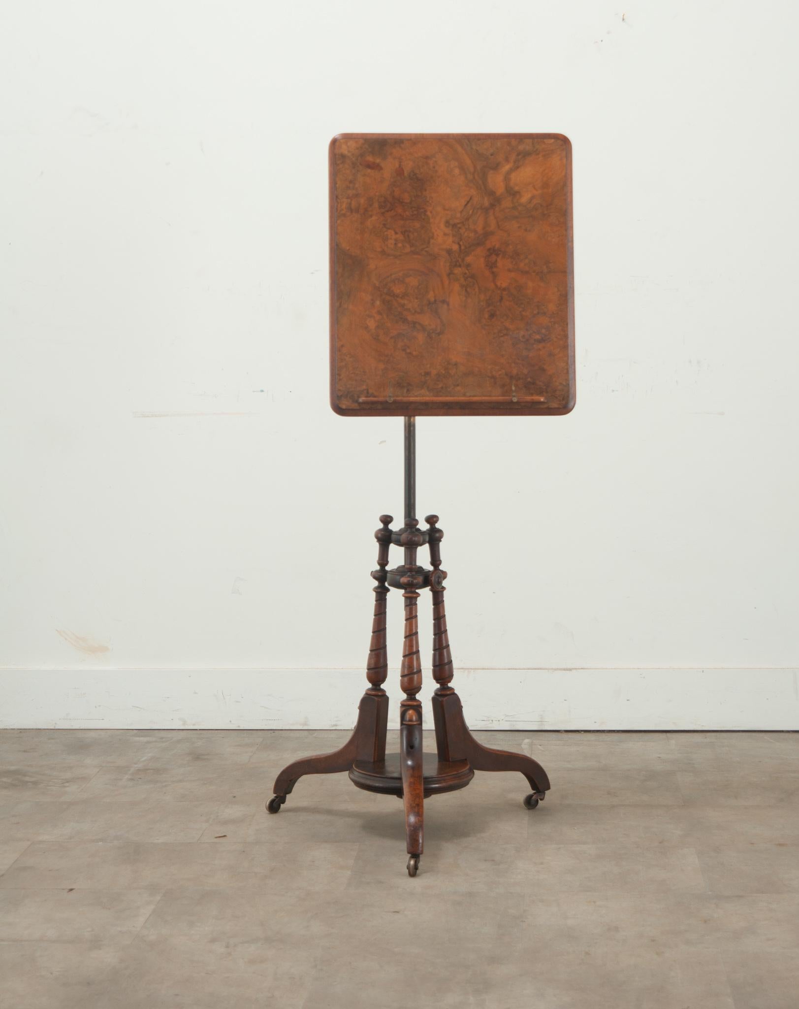 An English sheet music stand made from burl walnut and copper. This sheet music stand is unique with its burl walnut table top and copper center which allows the top to swivel and be adjusted. The stand is raised on a carved and turned pedestal base