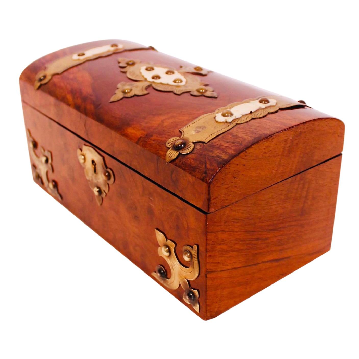 A handsome Victorian era burl wood tea caddy retaining much of its interior silvering. The exterior is adorned with ornamental brass strapwork elements, studs and an escutcheon, the lid is further embellished with carved bone elements layered on top