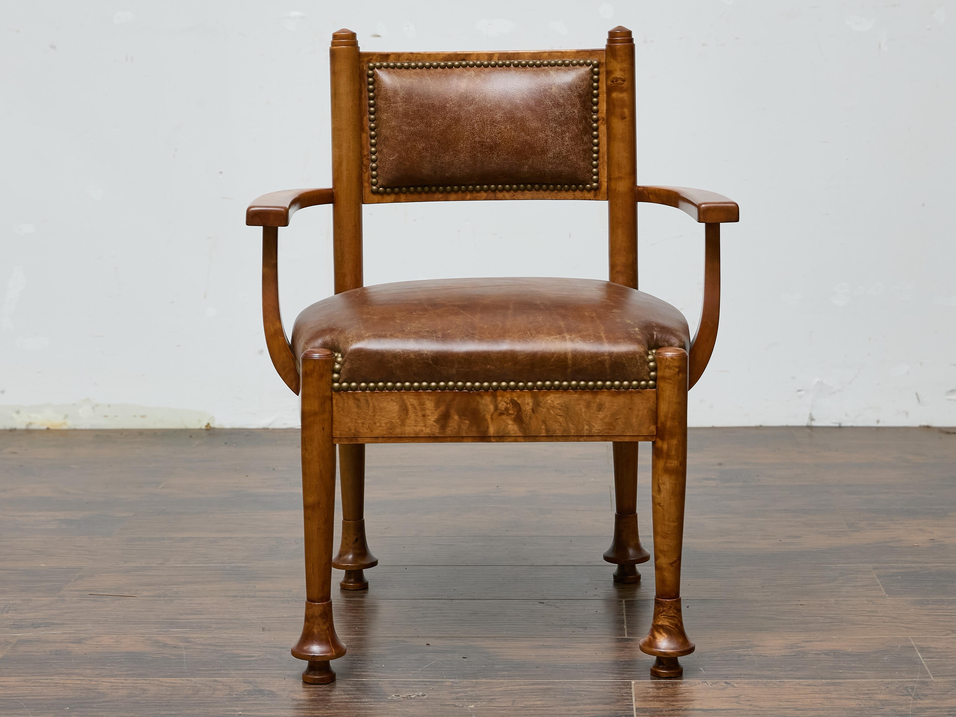 A finely crafted English armchair in burl wood, dating to the early 20th century, featuring a rich combination of clean architectural lines and refined details. The shaped seat and rectangular padded backrest are both upholstered in a warm brown