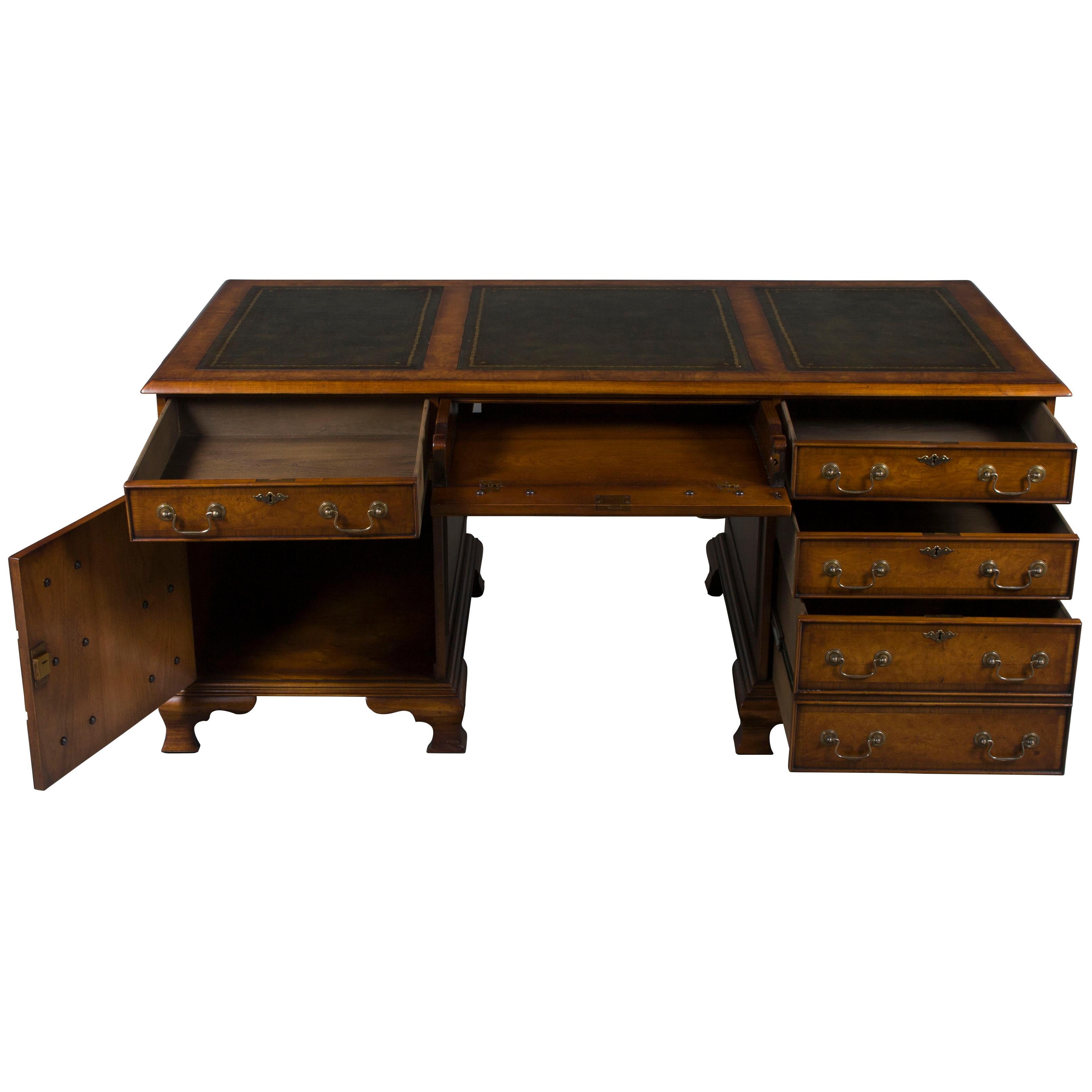 This beautiful walnut pedestal desk is English-made by hand as a Georgian period reproduction. The walnut boasts a rich complexion, enhanced by hand-finished surfaces and complemented by lovely cross banding and antiqued escutcheons and solid-brass