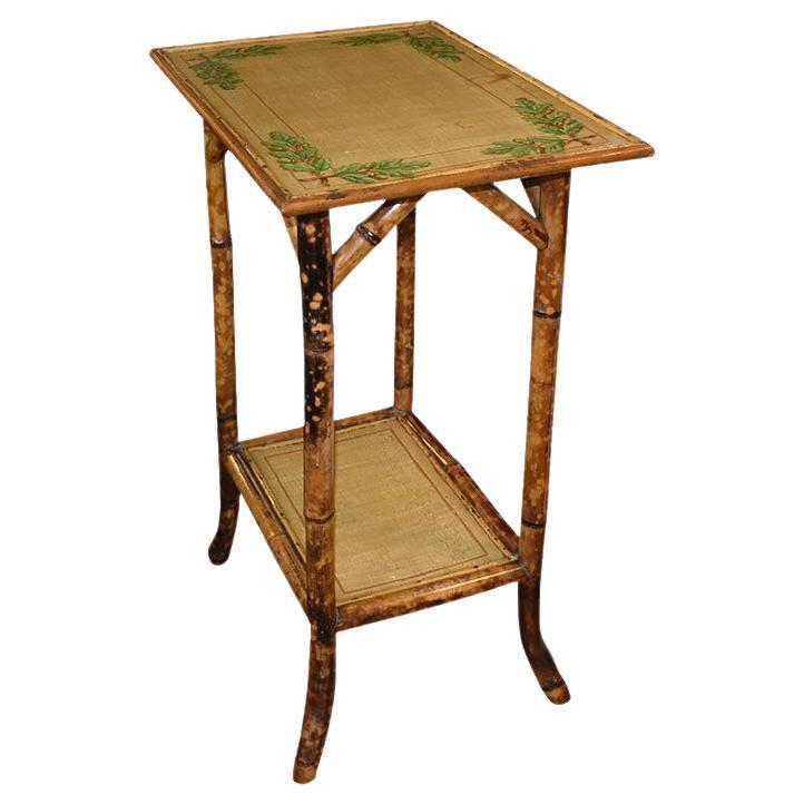 A tall English rectangular bamboo side table with a bottom shelf. This end table will be fantastic in any room and will fit well with Chinoiserie, Grand Milleniel, and traditional decor. Rectangular in shape, the top is of wood, with a flora motif