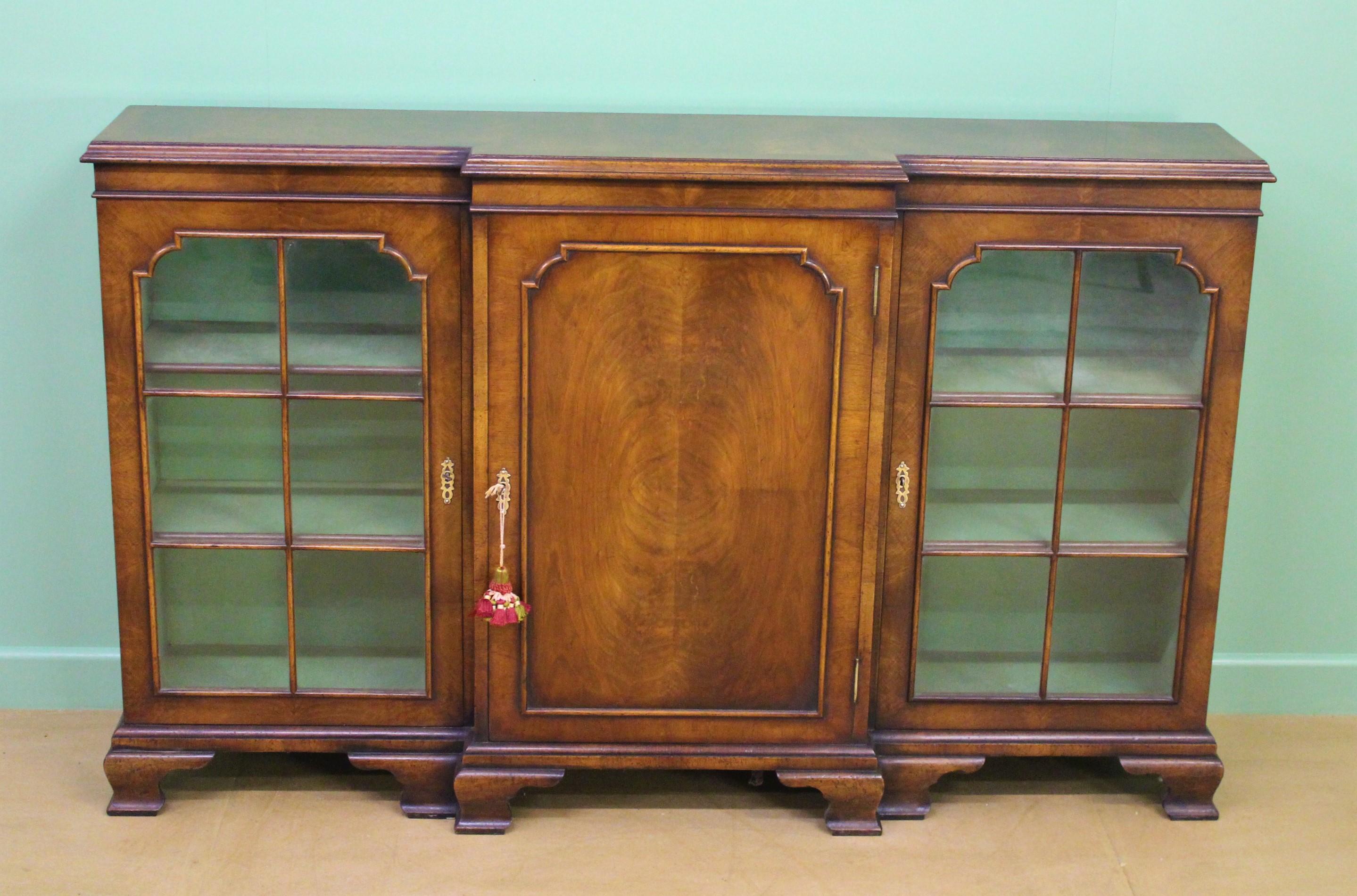 A handsome Georgian style burr walnut breakfront bookcase. Well made in solid walnut with attractive burr walnut veneers onto an oak carcas. The top is cross banded. With a central cupboard door, flanked by a pair of glazed doors. Each door is