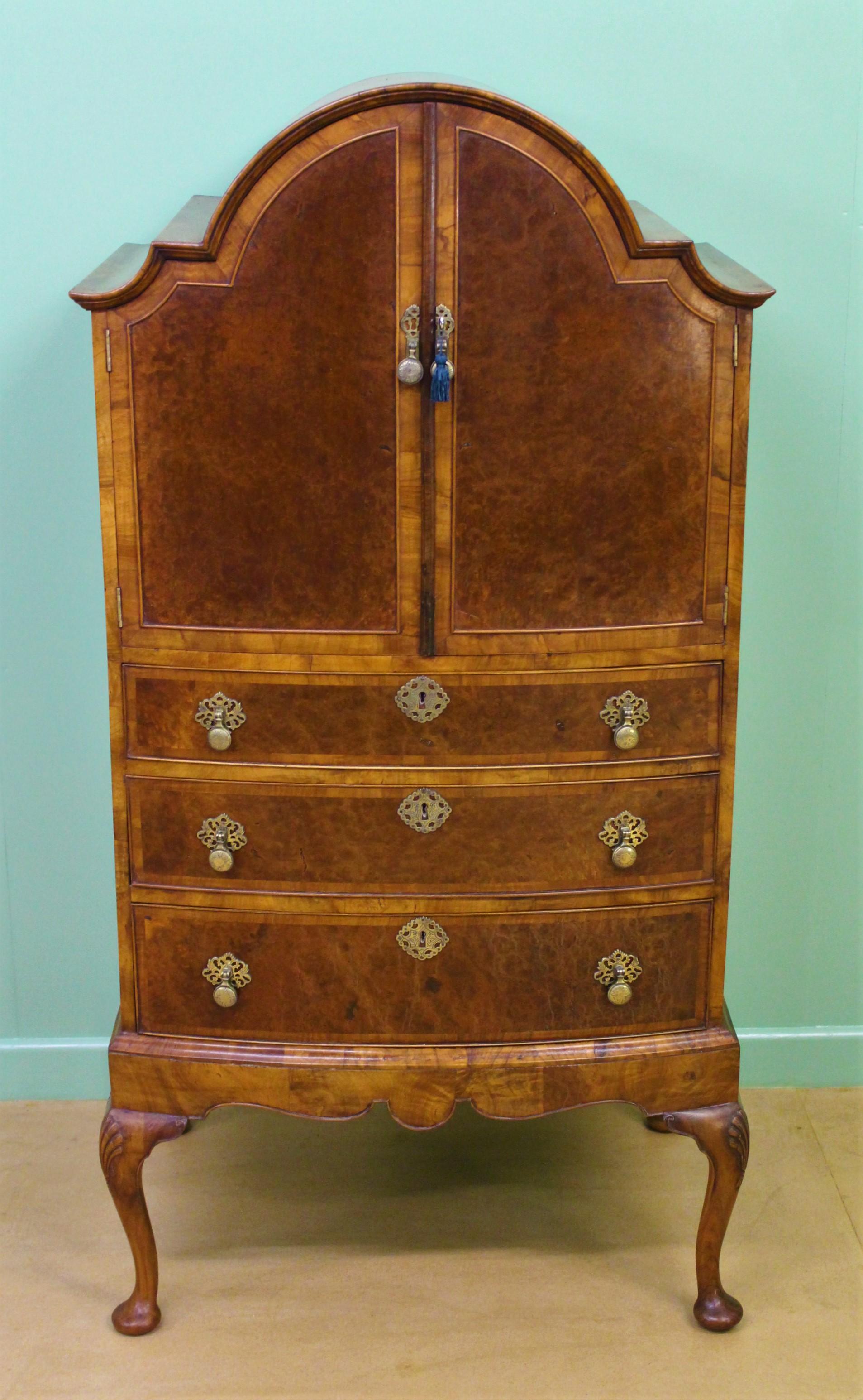 A charming burr walnut, bow-fronted, dome topped linen press of compact proportions. Well made in the Queen Anne style in walnut and with attractive burr walnut veneers. The domed top section has a pair of doors that open to reveal a shelved