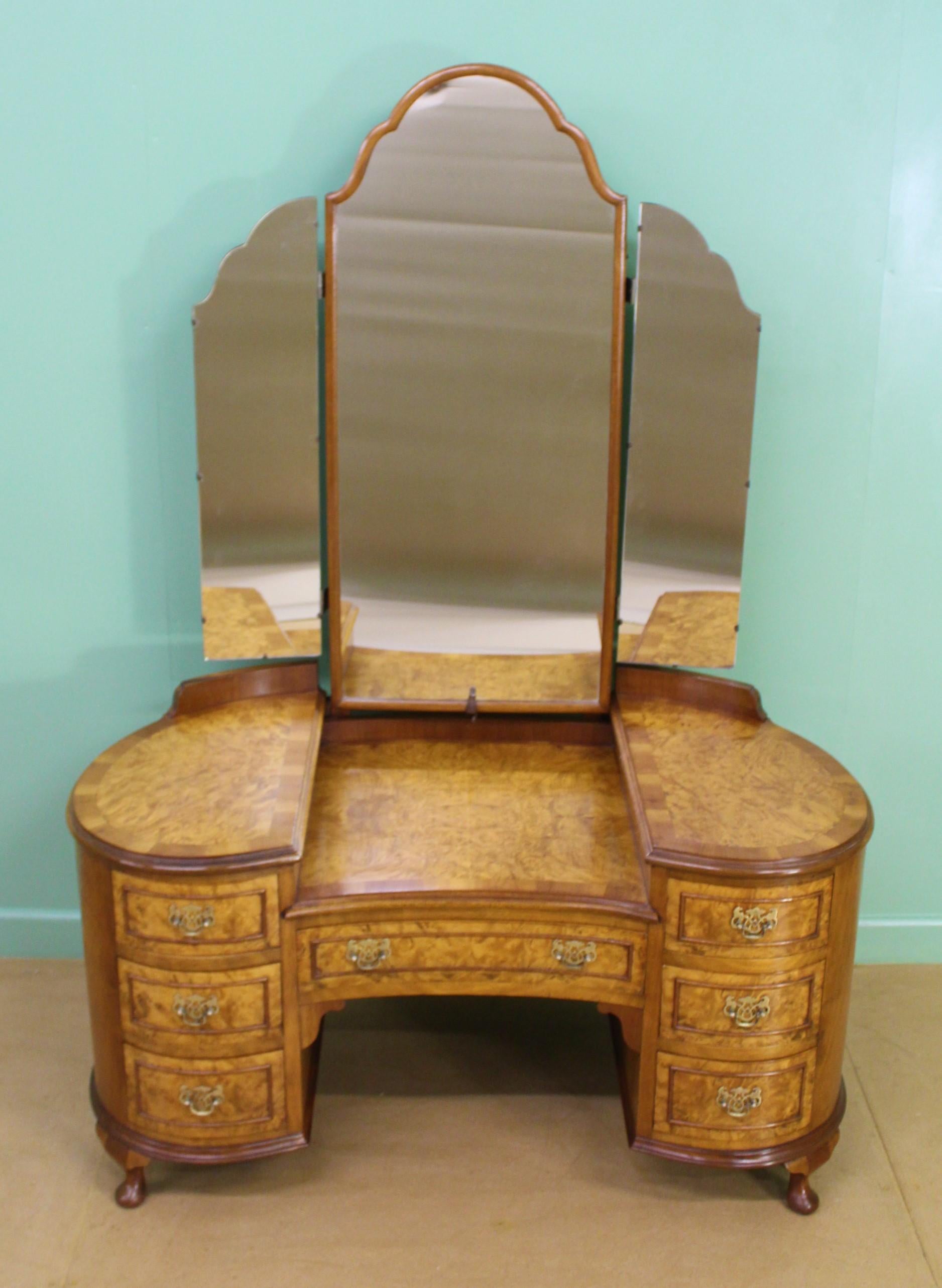 A charming burr walnut kidney shaped dressing table in the Queen Anne style. Well made in solid walnut with attractive burr walnut veneers. The triple mirrors are adjustable and in excellent order. The table is of kidney form and has an arrangement
