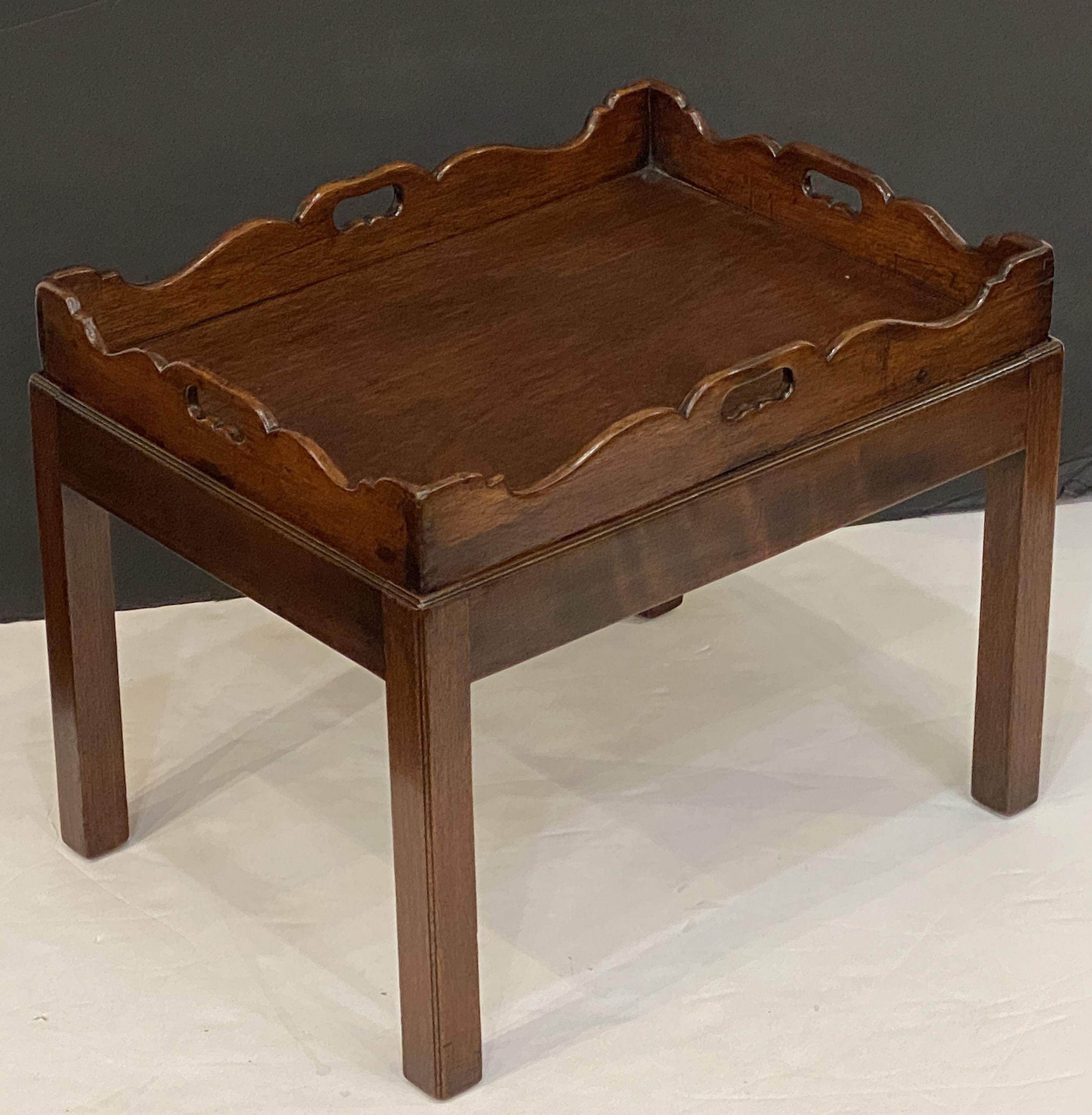 A handsome English end table or side table of oak, each featuring a removable serving or butler's tray, with a fitted stretcher base.

Great for display next to upholstered furniture!


