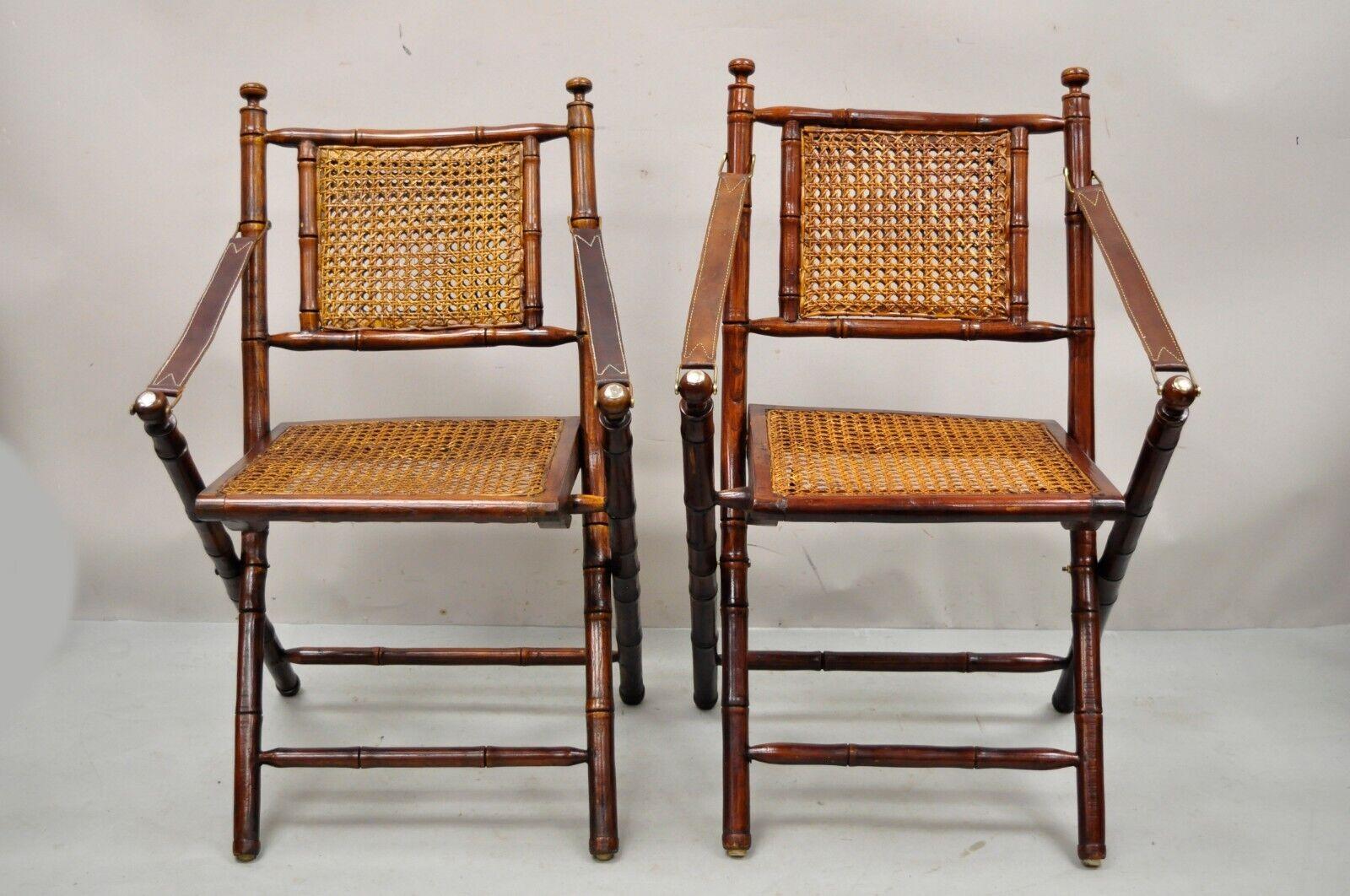 English Campaign Style Carved Wood Bamboo Folding Sling Arm Chairs with cane - a Pair. Item features cane back and seat, leather sling arms, folding design, solid wood frames, distressed finish, great style and form. Circa late 20th Century - Early