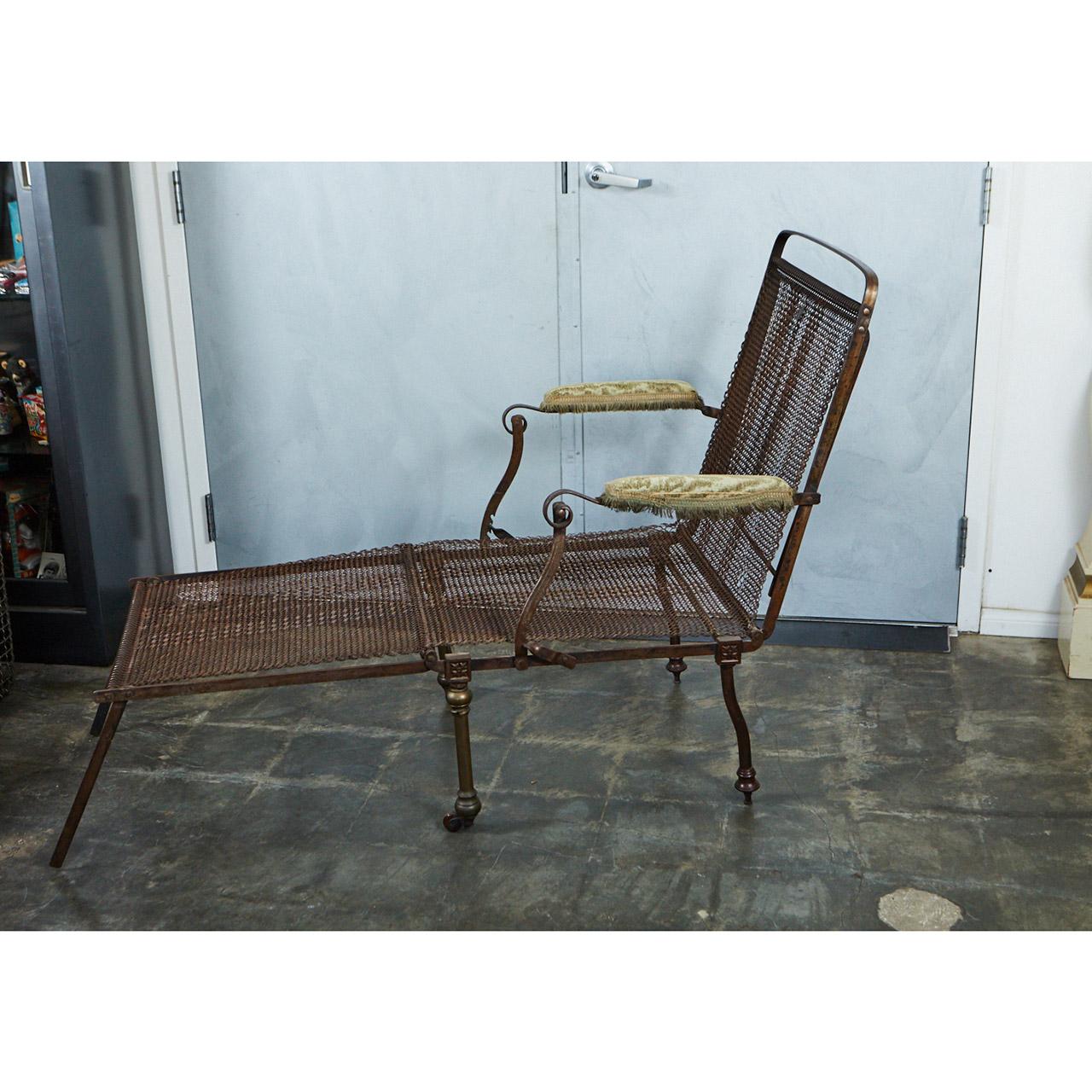 This unique piece of campaign furniture has an iron frame and woven metal body. It can be adjusted several ways to be used as a chair with or without a foot rest and also a bed with supports that fold out from the frame. The piece has upholstered