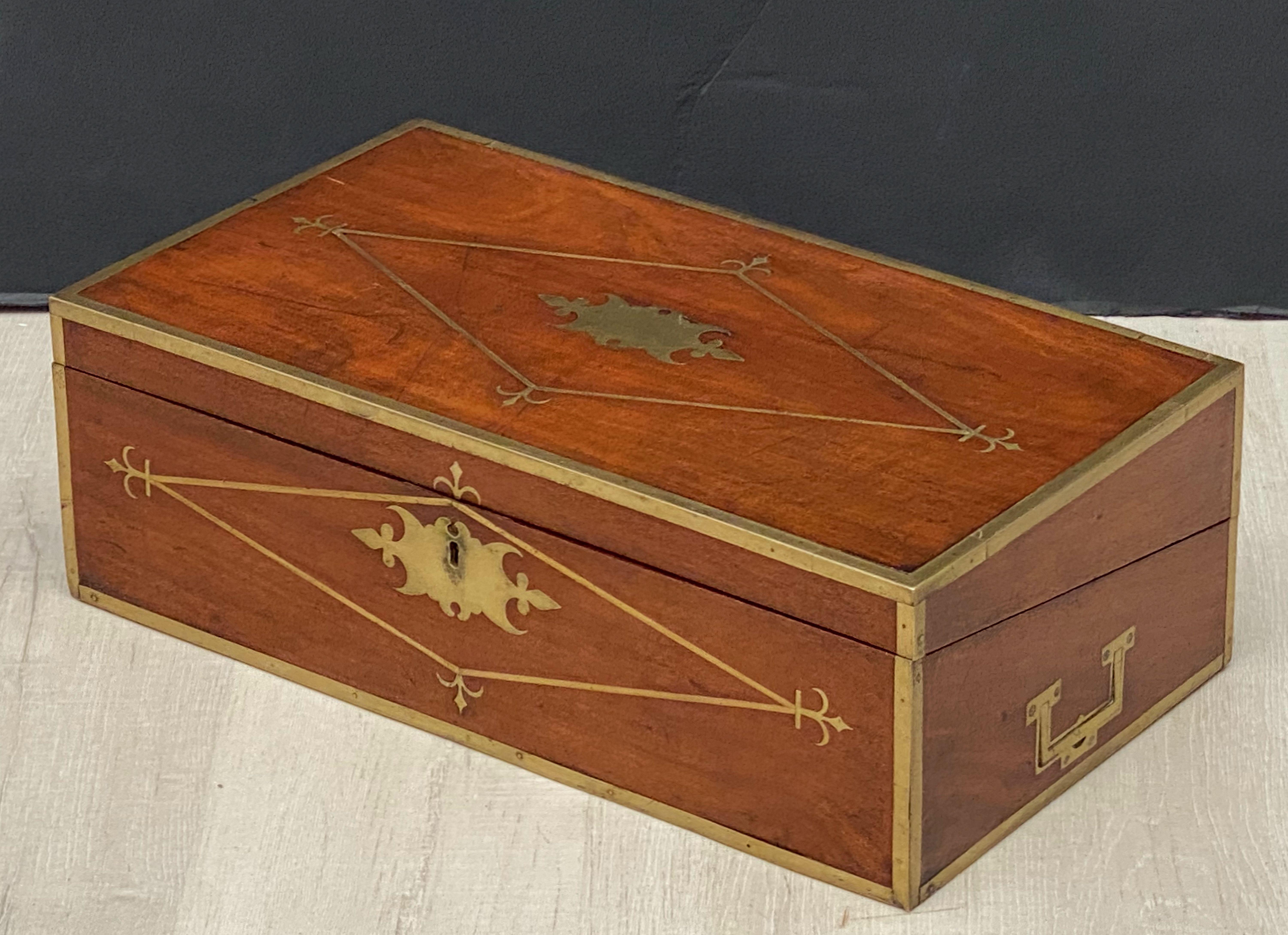 A fine English military officer's writing slope (or Captain's box) of brass-bound mahogany, from the Campaign Era, featuring a two-section hinged interior that opens to become a writing desk, with compartments for inkwells, writing pens, and
