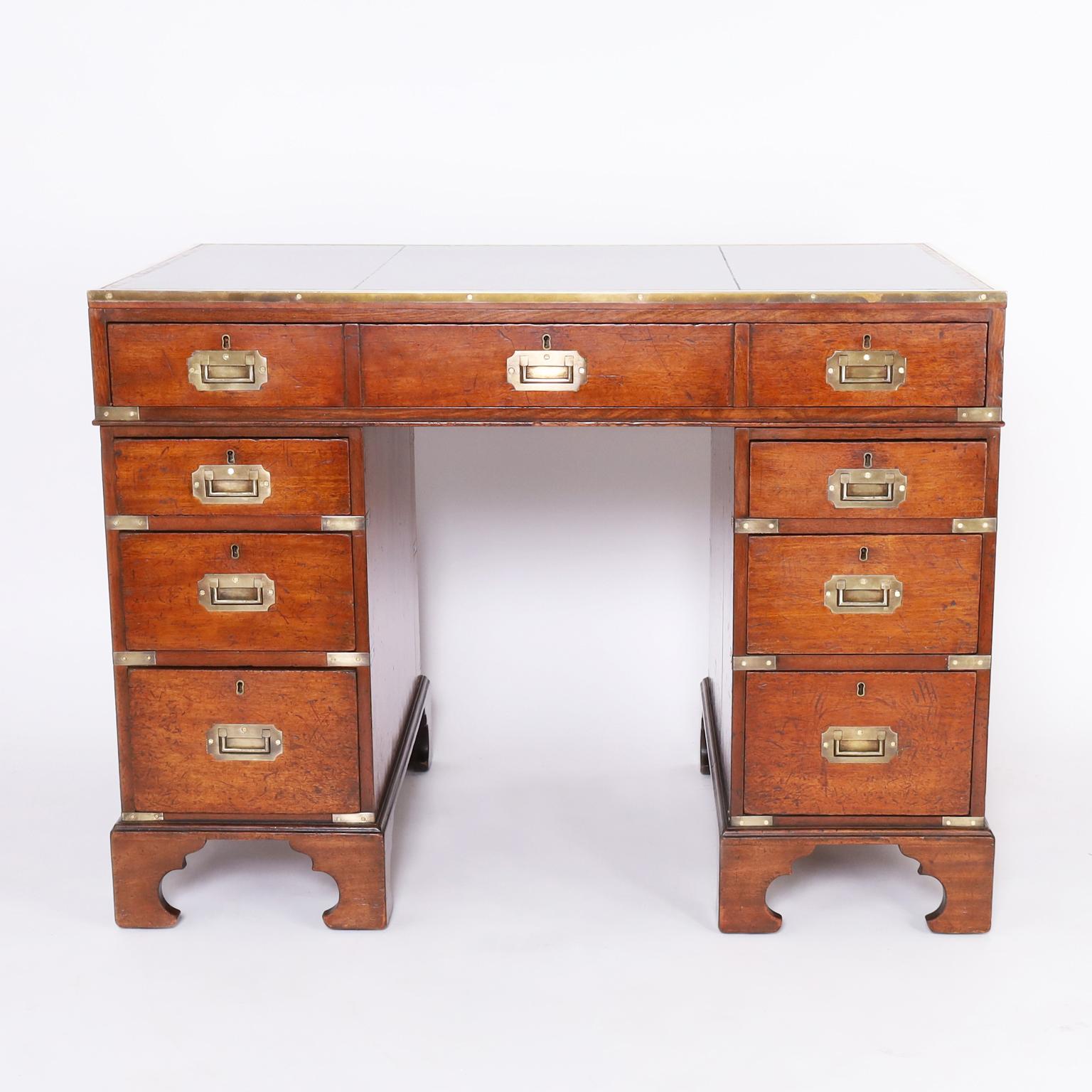 Handsome 19th century English desk handcrafted in mahogany with a tooled leather top, three piece campaign construction, brass hardware, and classic bracket feet. 

Kneehole measures 24.5
