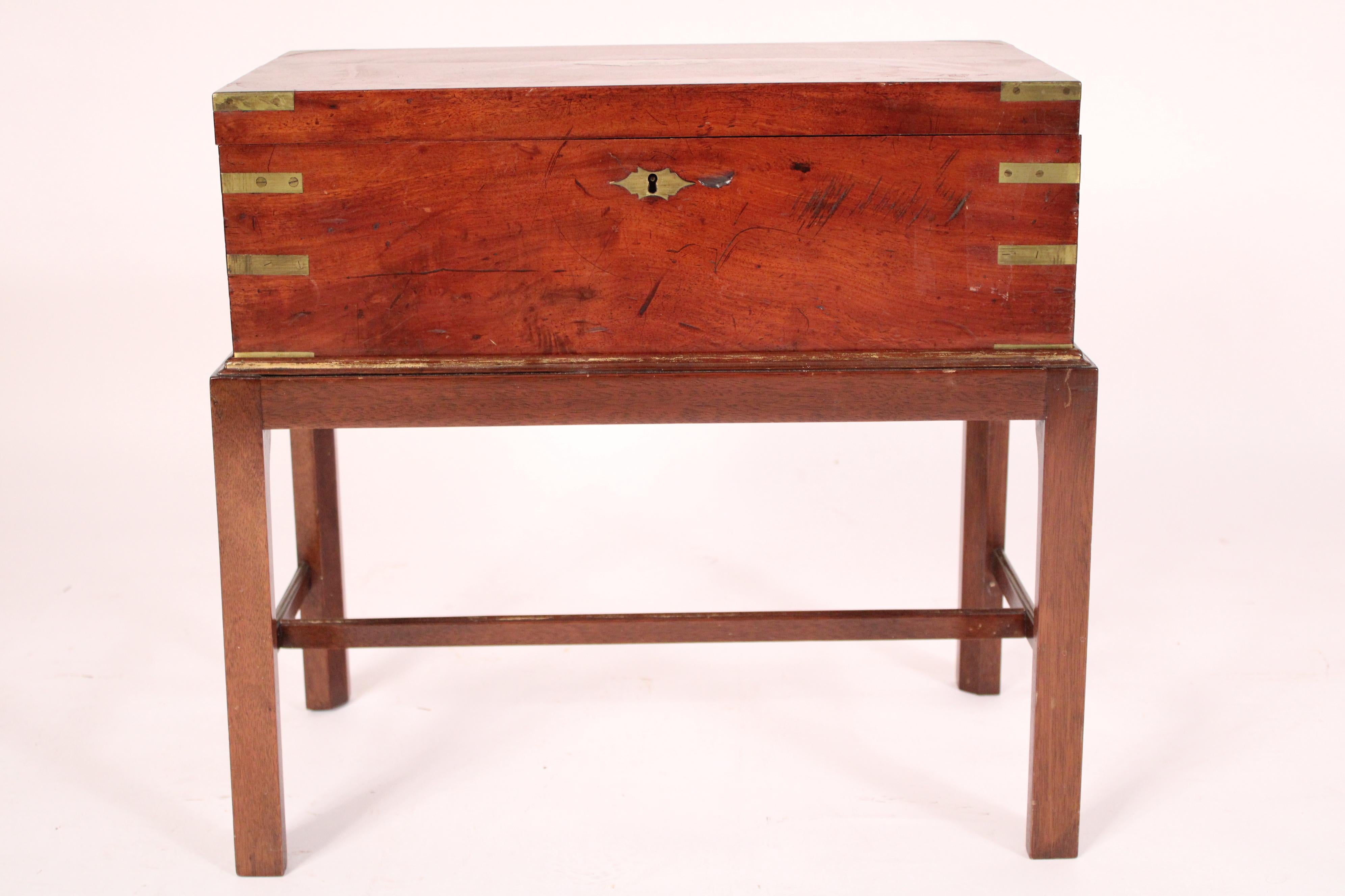 Campaign style brass mounted mahogany English traveling desk, late 19th century on a late 20th century stand. The rectangular mahogany top inset with a central plaque that reads 