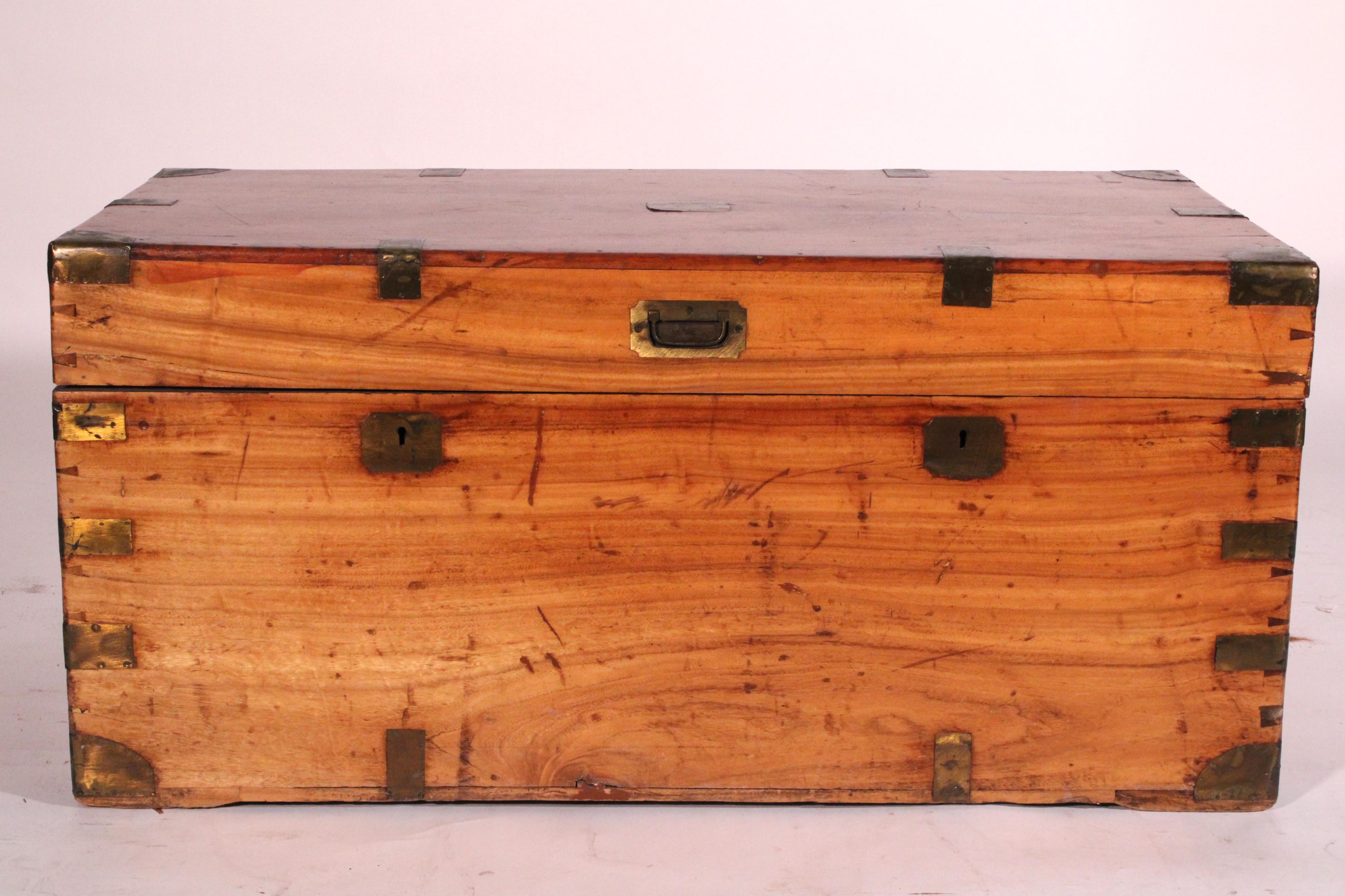 English camphor wood campaign trunk, circa 1900. With a rectangular hinged top with a central brass plaque the edges of the top with brass straps, the corners with brass mounts, the inside of the trunk is cedar lined, the front and sides and back of