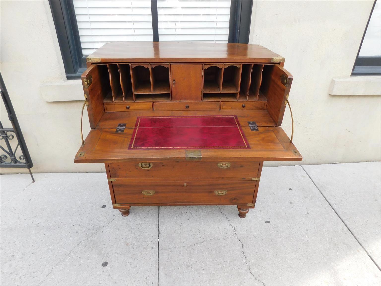 Cassettone militare inglese in legno di canfora con cassetto superiore incernierato che rivela un piano di scrittura in pelle, porta centrale con chiave, buchi per piccioni, tre cassetti interni con tiretti, quattro cassetti inferiori graduati,