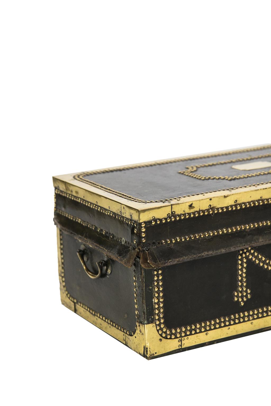 English camphor wood trunk is overlaid with leather and bound with brass strapping and stud work. Some studs are missing.
   