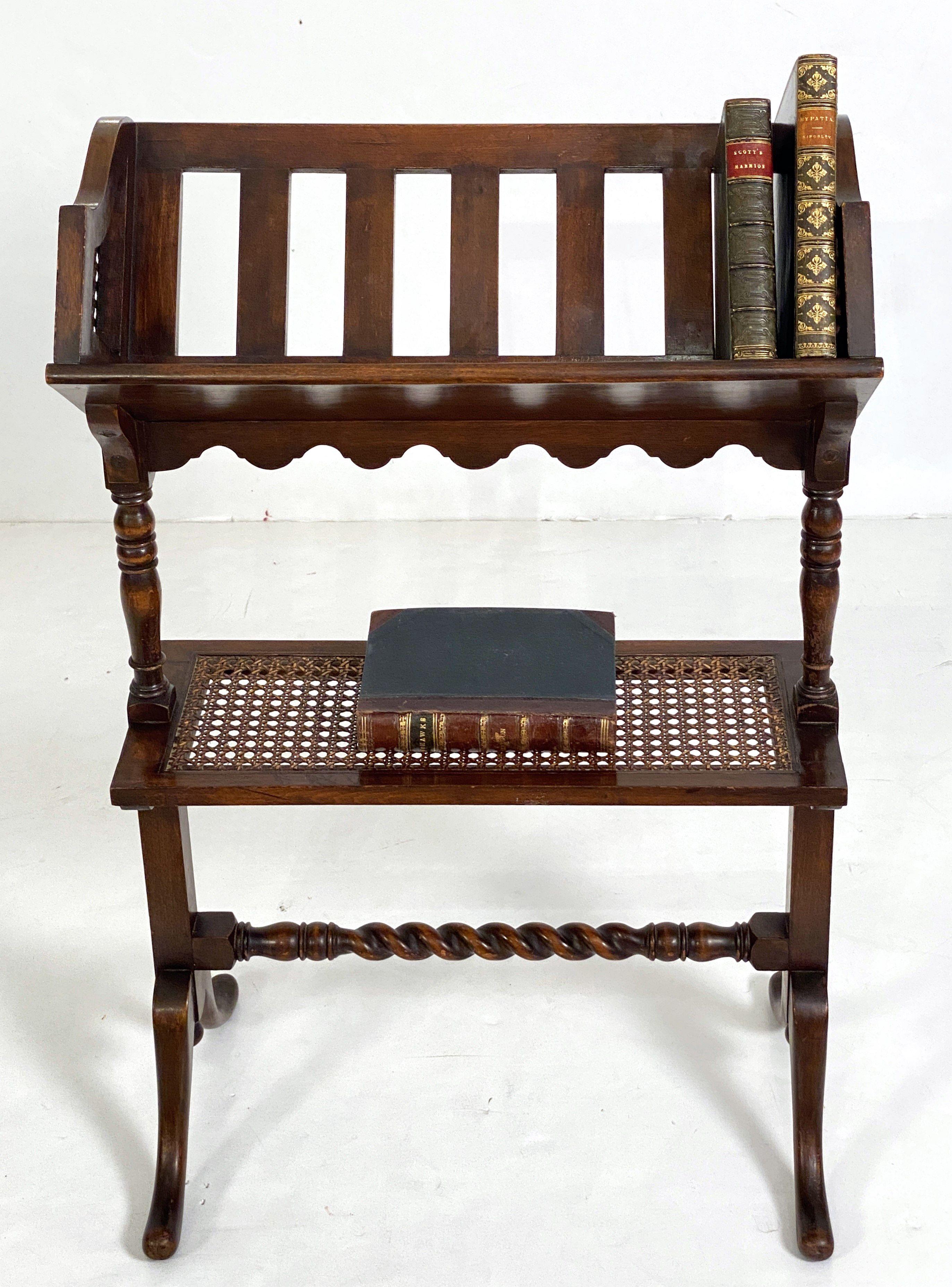 A handsome English two-tiered book trough or library book stand of beech-wood from the Edwardian era, featuring a canted and half-slatted upper tier with caned bergere sides (for display of books) over a flat bottom tier caned bergere shelf (where