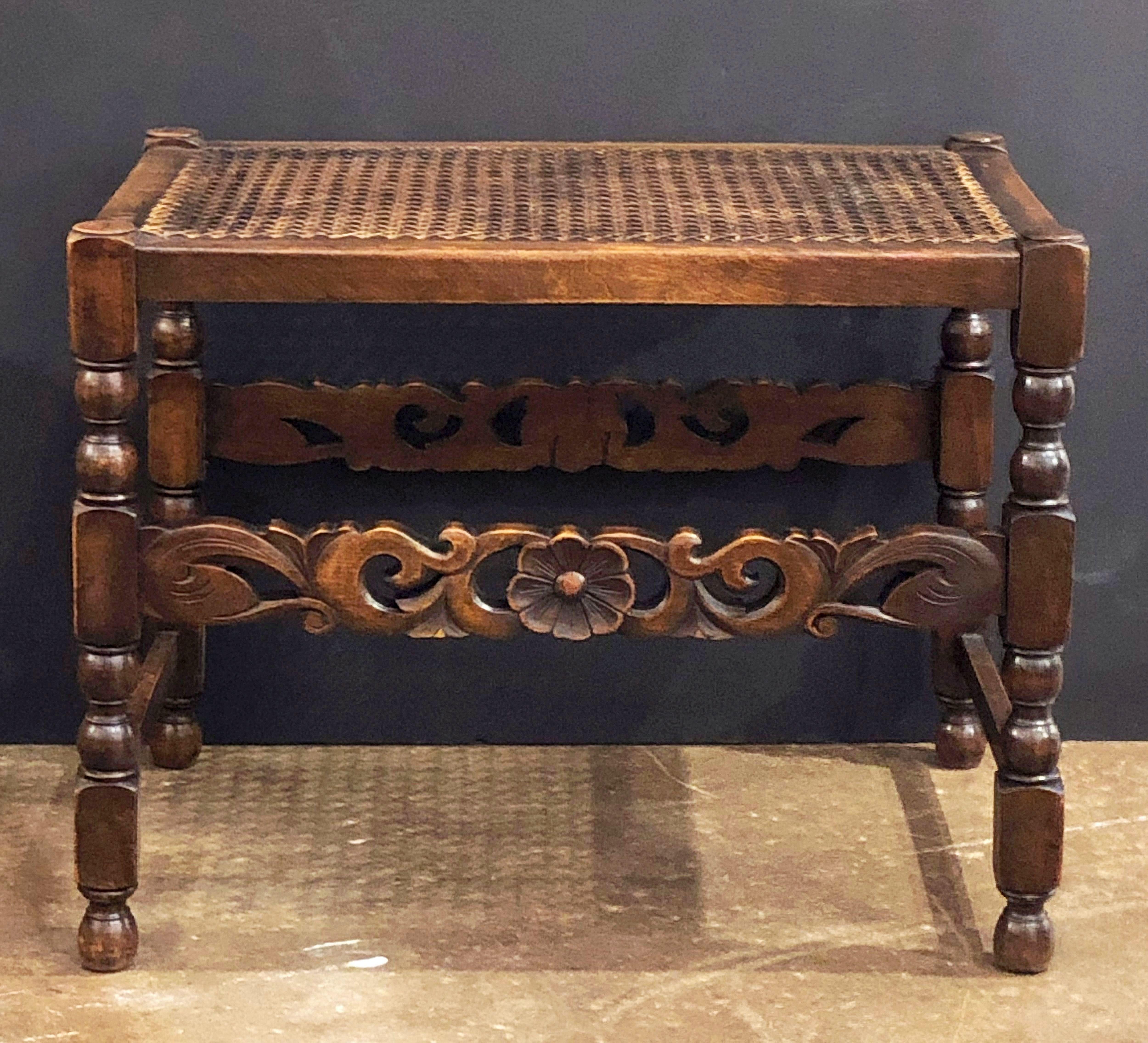 A fine English bergère stool or bench seat featuring a caned top or seat with a turned wood stretcher and carved wood decorative supports.

Dimensions: H 18 1/2 inches x W 24 inches x D 16 inches