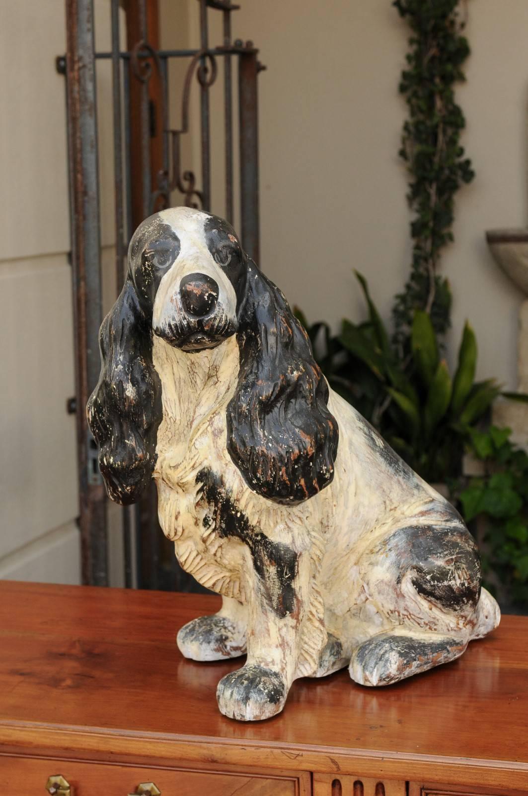 Une sculpture anglaise de chien épagneul en bois sculpté et peint de la première moitié du 20e siècle. Née pendant les années folles, cette sculpture de chien en bois représente un bel épagneul cocker, assis tranquillement, les yeux fixés sur une